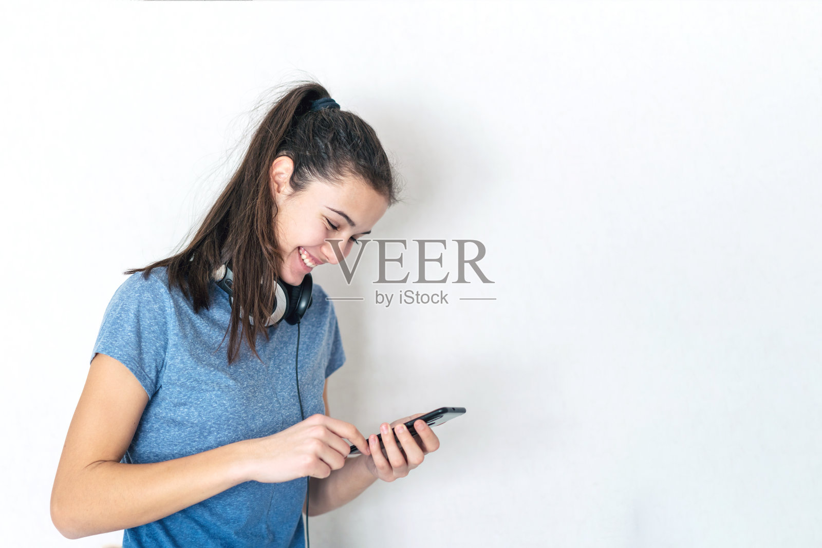 戴着耳机用智能手机打字的少女照片摄影图片