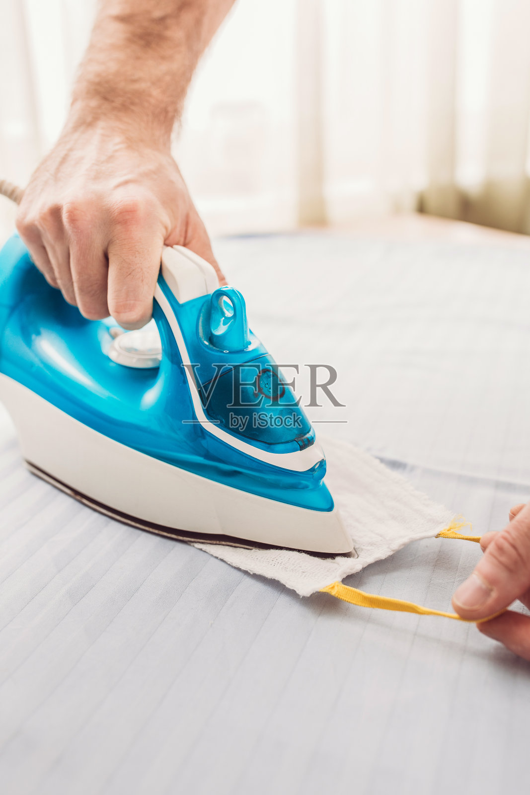 一名男子用铁器加热纱布面罩，以消灭细菌-抗菌治疗照片摄影图片