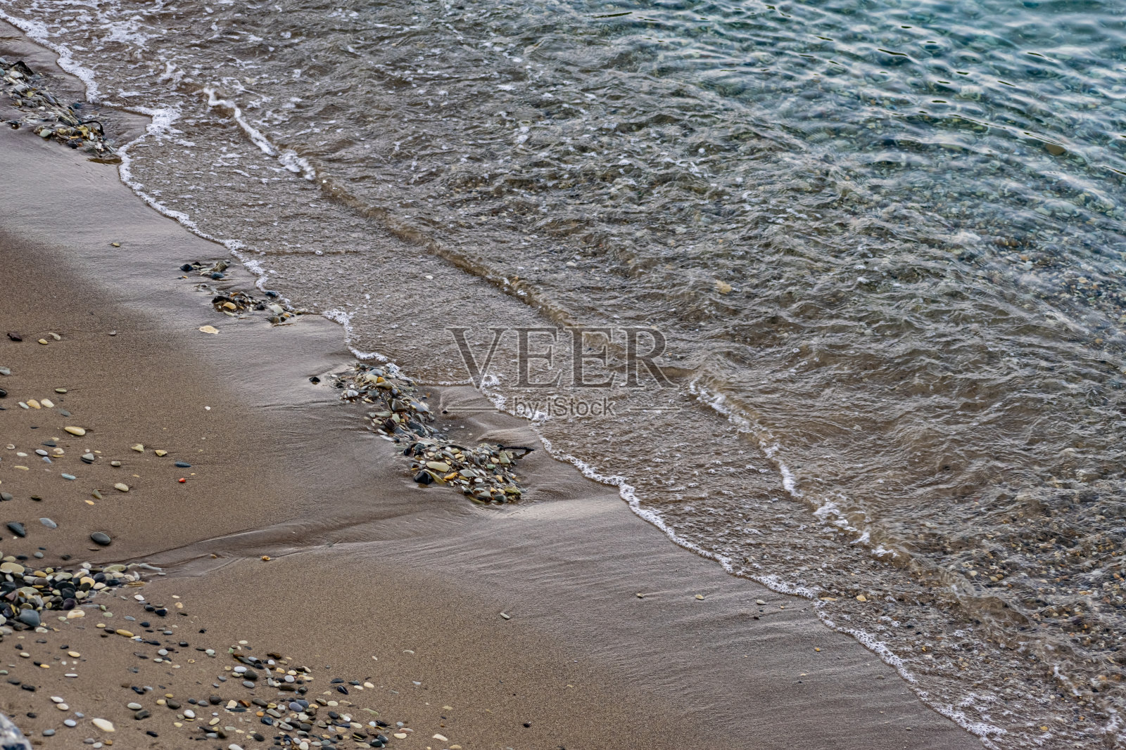 水面是咸咸的海水，在岸边的小波浪中摇曳，透过透明的海底你可以看到石头照片摄影图片