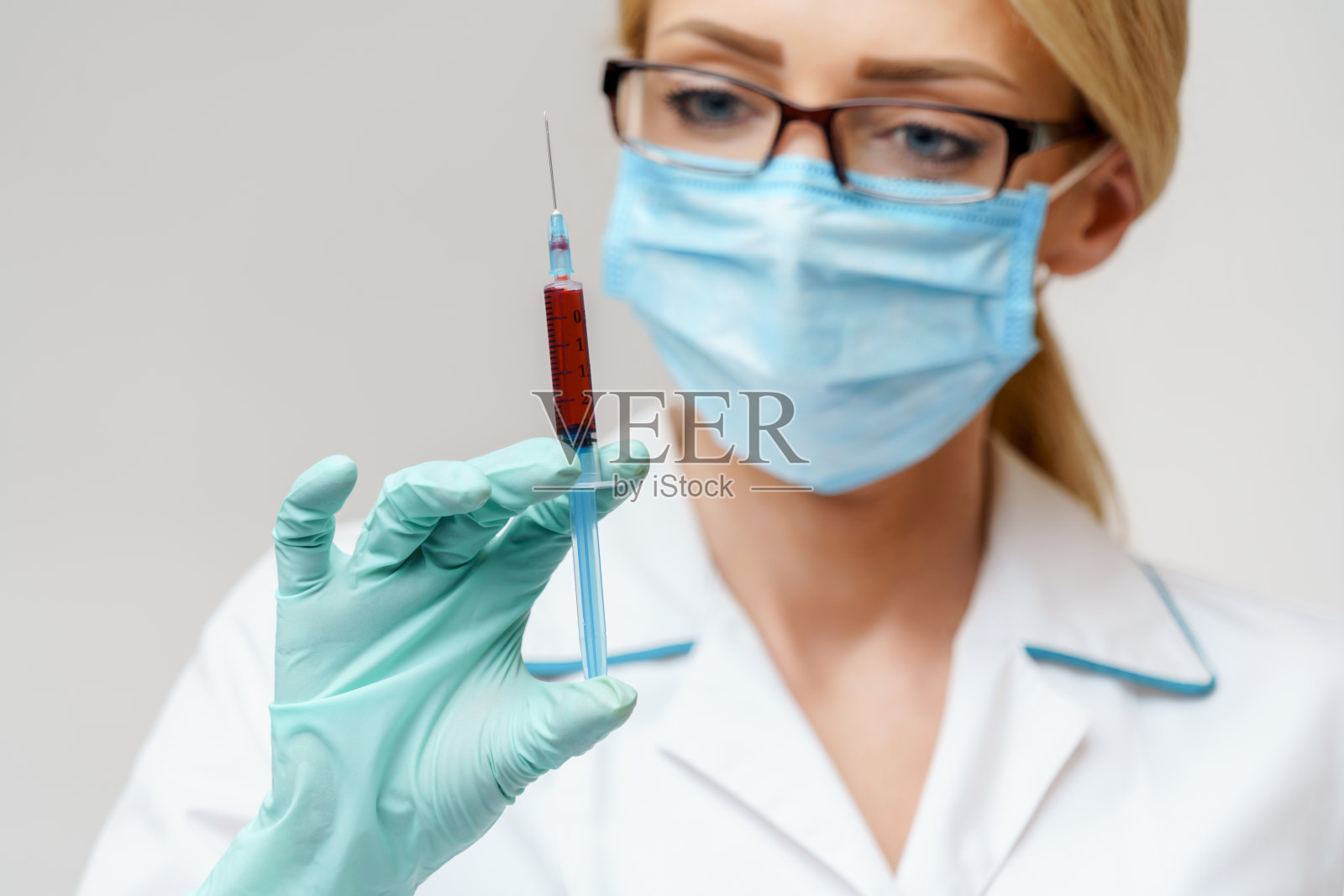 医生或女护士戴防护口罩，手持注射器照片摄影图片