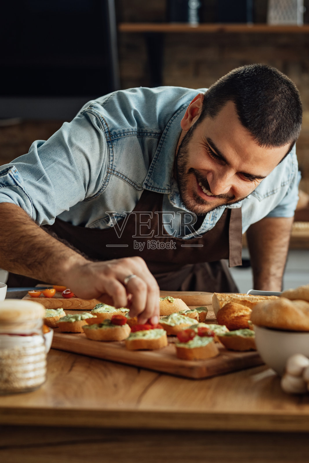 微笑的年轻人在厨房里准备意式烤面包。照片摄影图片