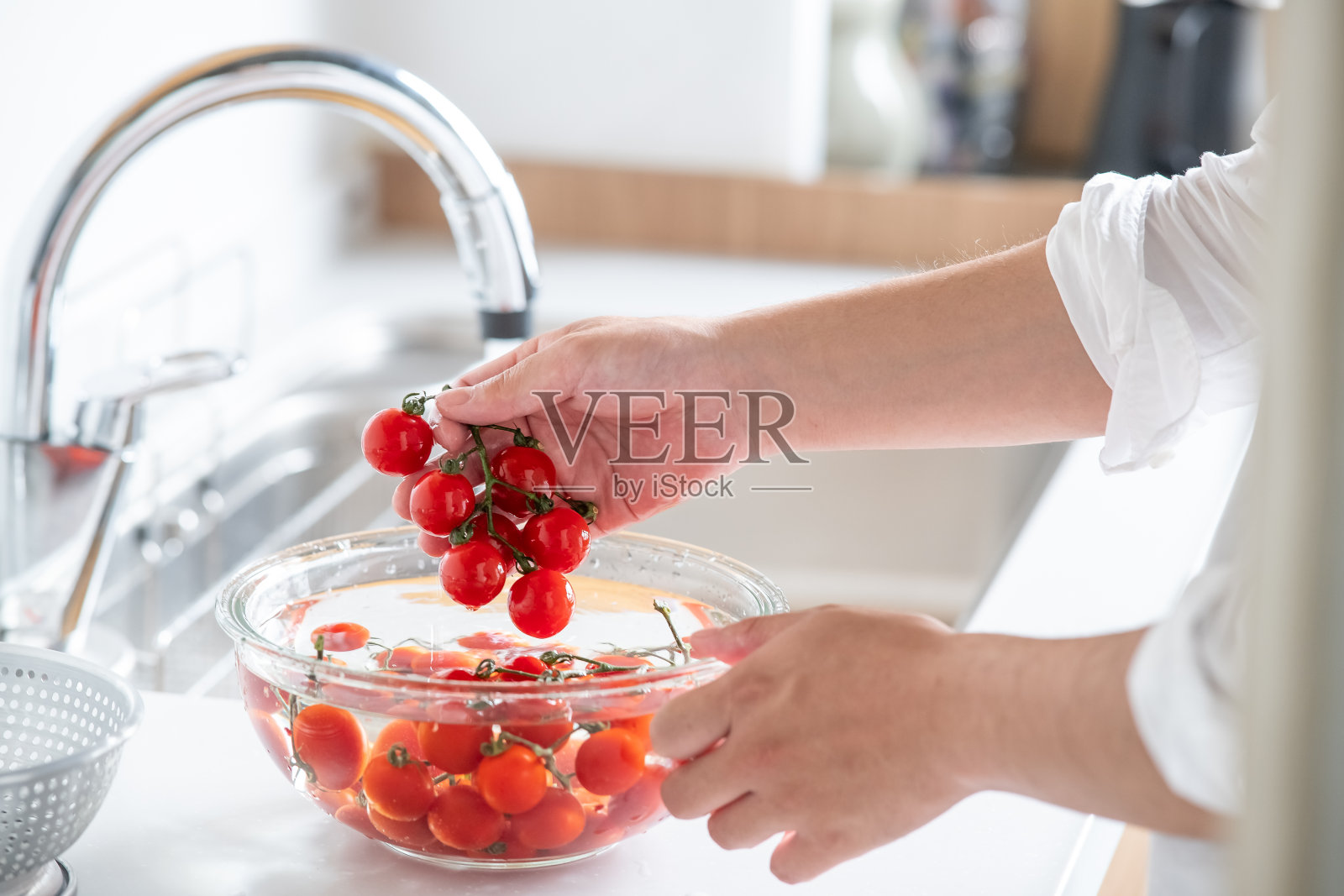 在厨房洗樱桃番茄的人。照片摄影图片