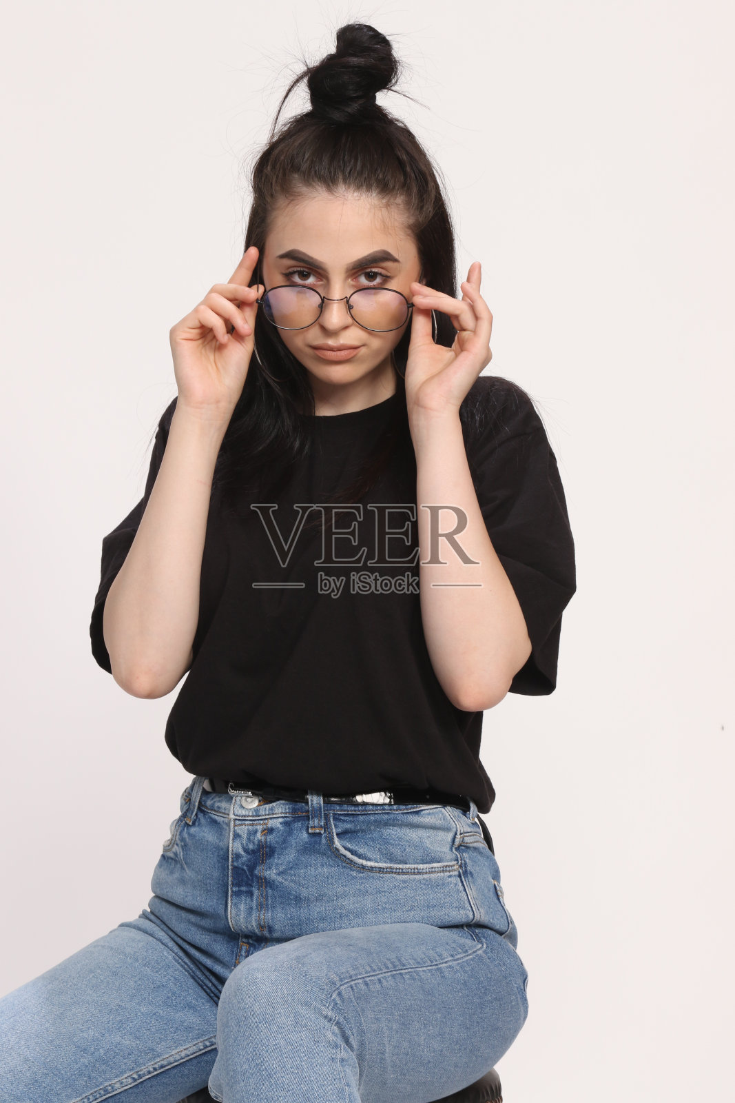 美丽的白人嬉皮士女孩与黑色头发和眼镜是在工作室摆姿势在孤立的背景。照片摄影图片