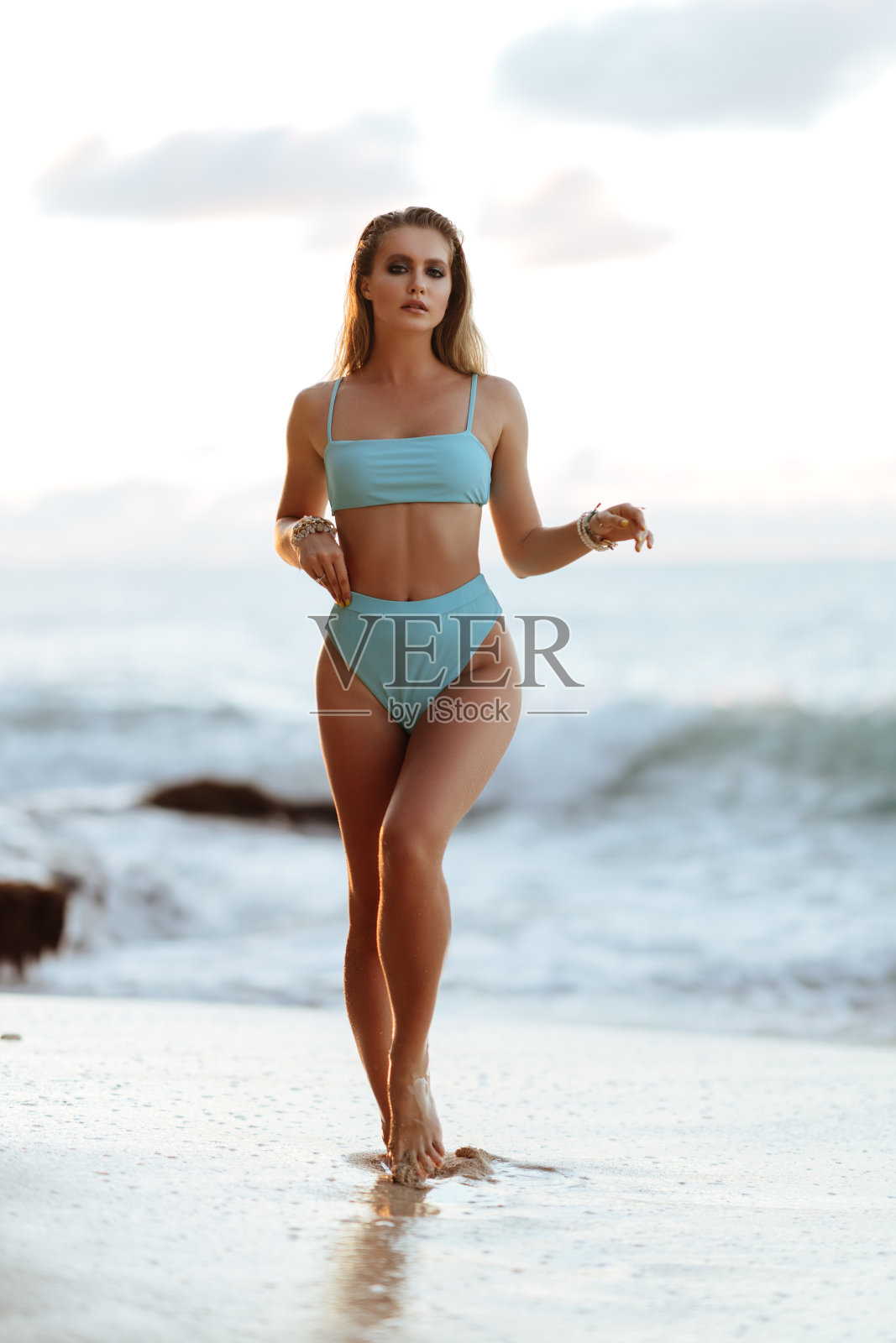 美丽和时尚的年轻女人在海滩摆姿势。照片摄影图片