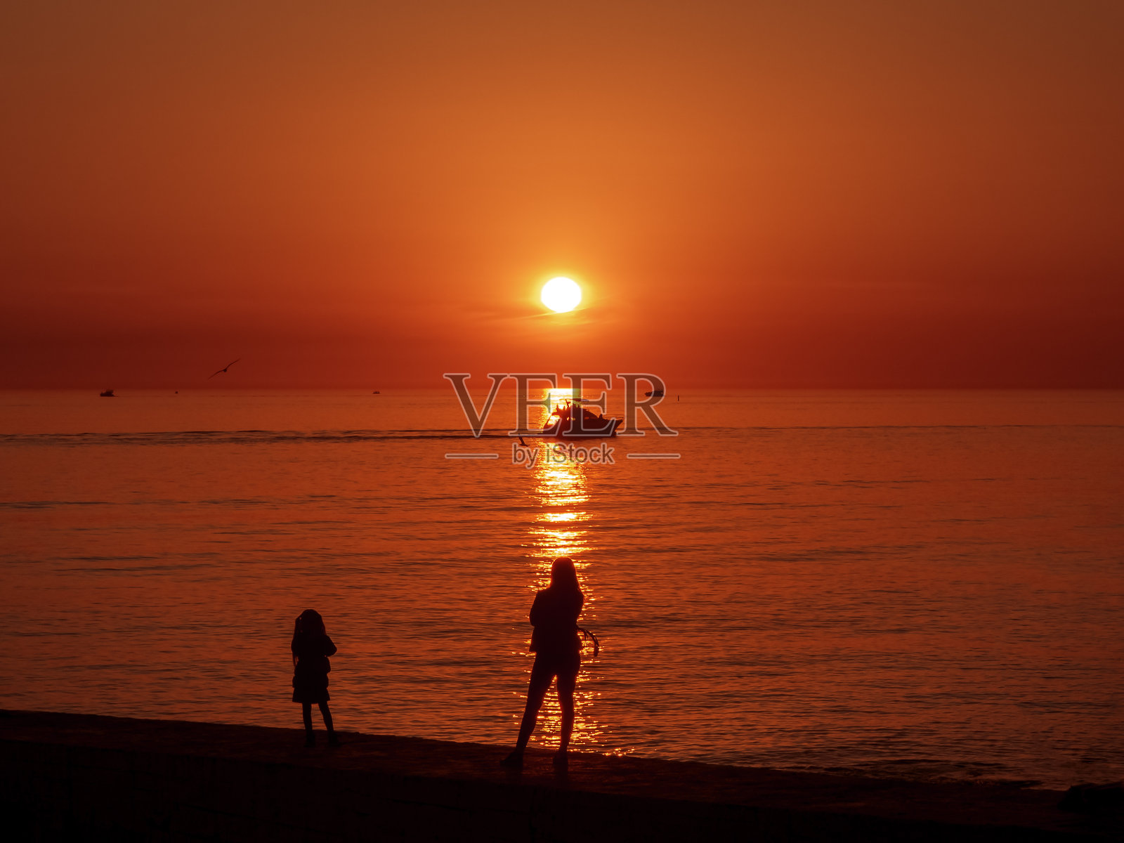 妈妈和女儿在码头上看美丽的海上日落照片摄影图片