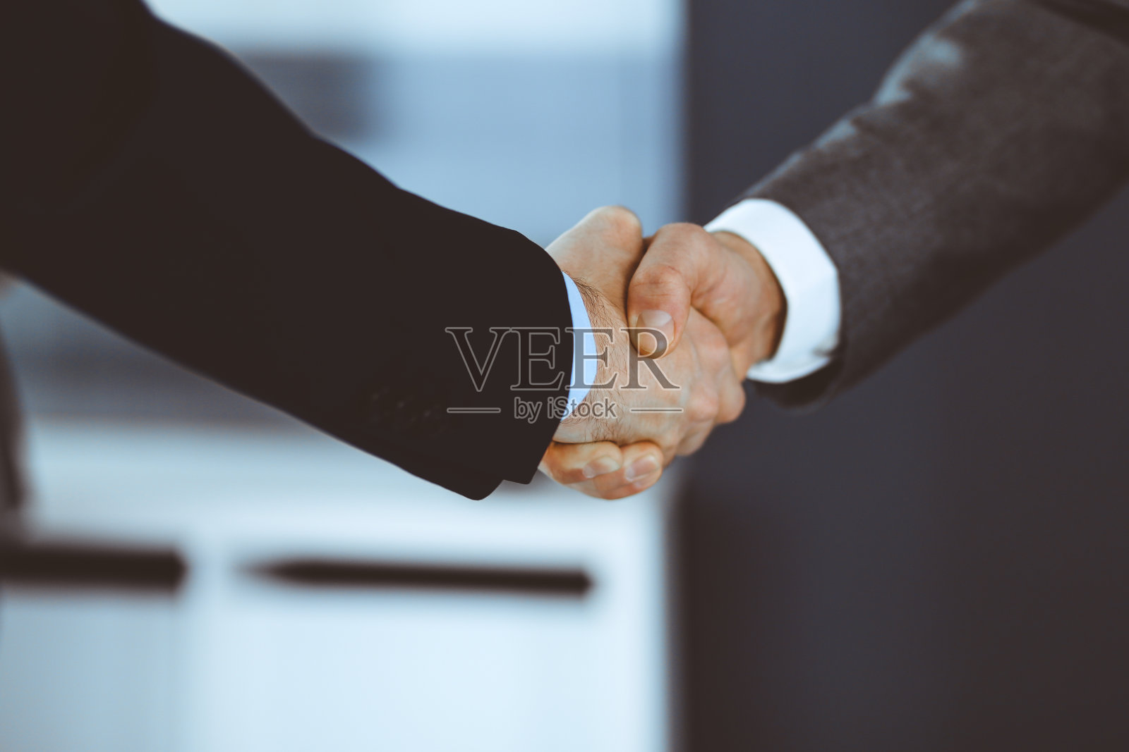 商务人士在会议或谈判后与同事握手。一群不知名的商人和女性在现代办公室。团队合作，伙伴关系和握手的概念，色调图片照片摄影图片