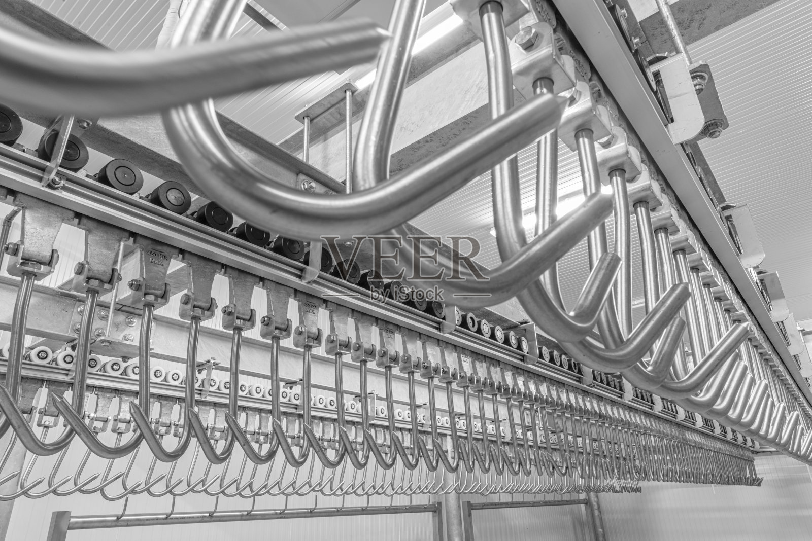 冷库仓库内的工业装卸码头区域。吊肉钩挂在轨上。照片摄影图片