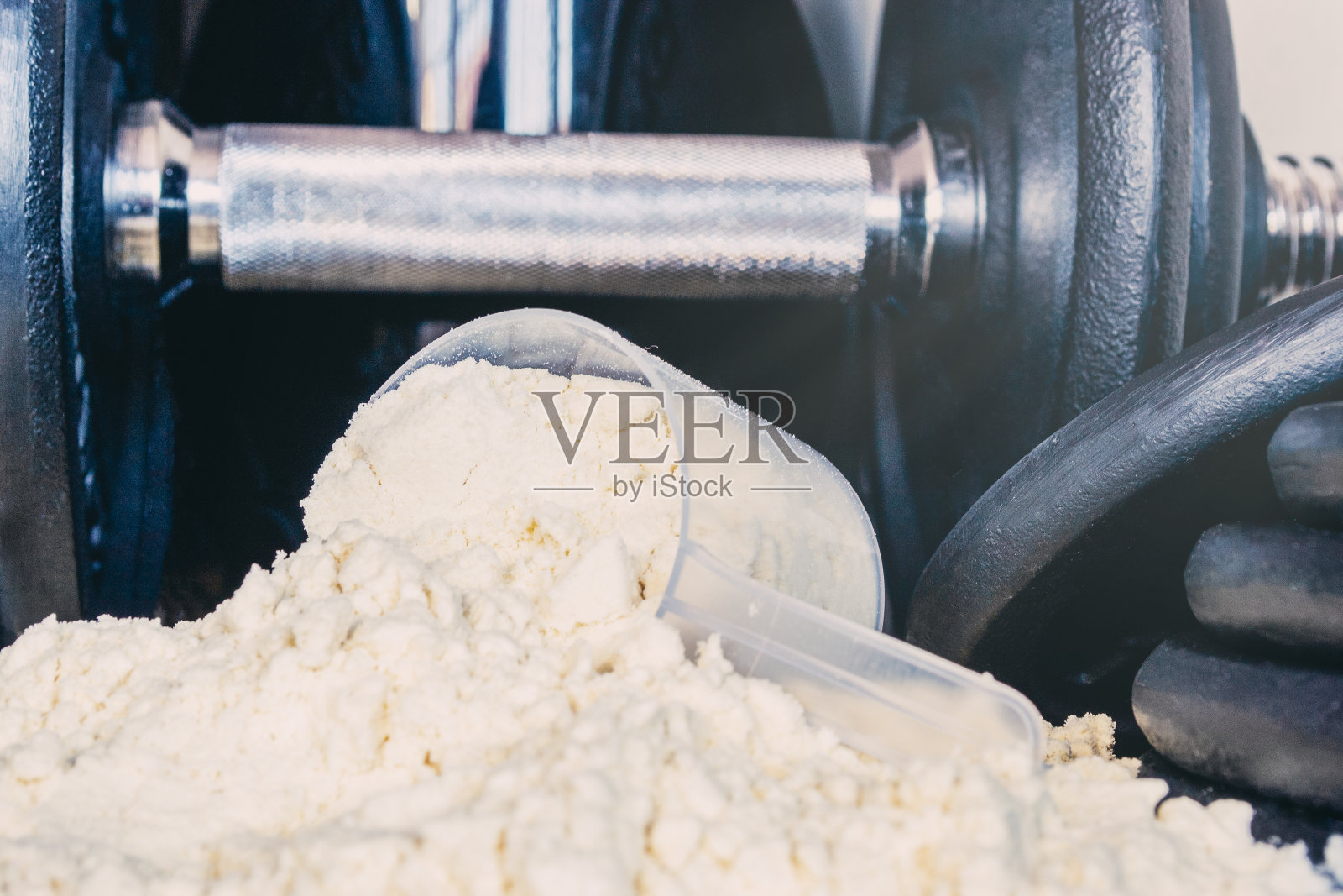 一匙乳清蛋白粉的前景，以重量为背景。运动营养照片摄影图片