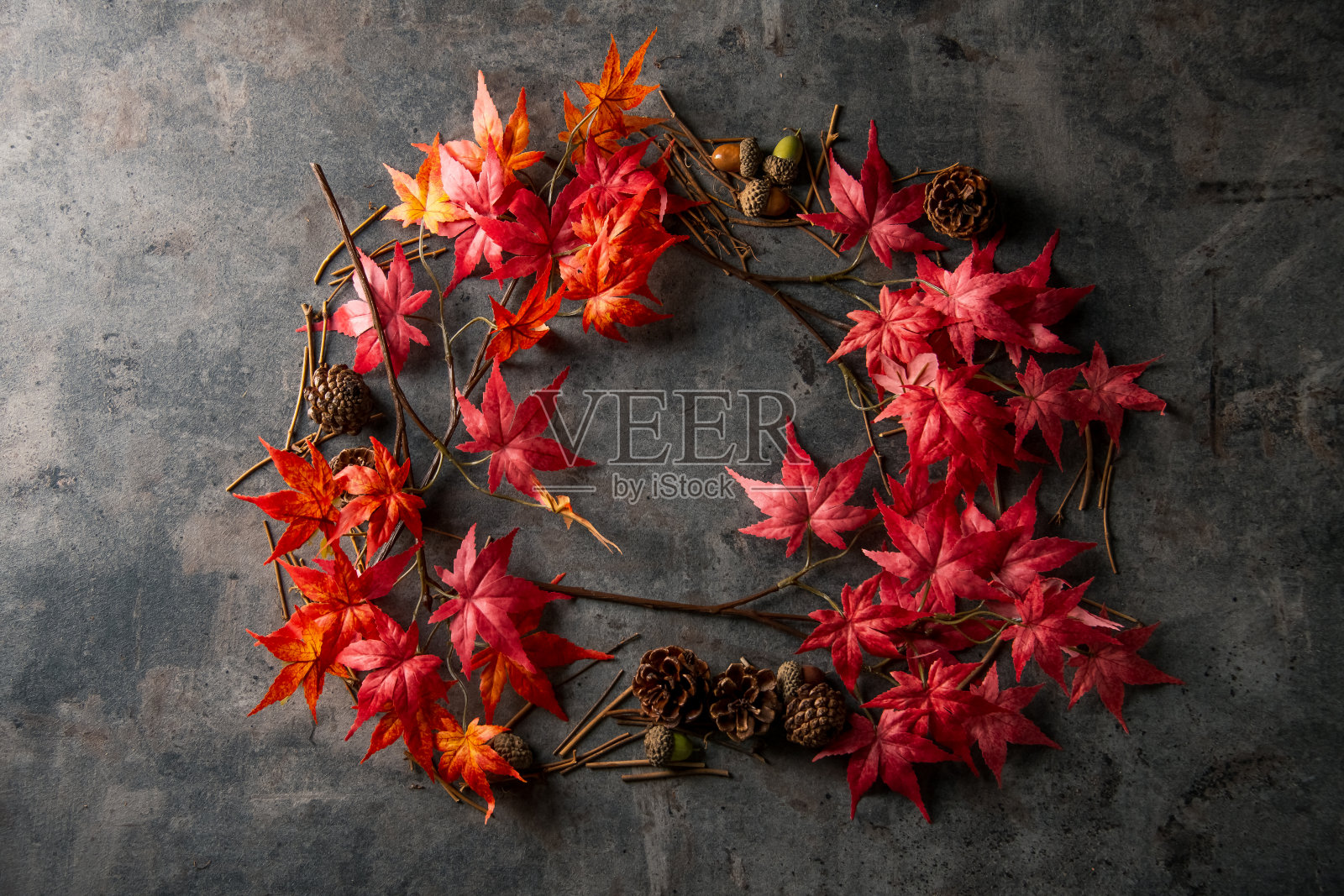 人造红色枫叶在深色的石头背景。照片摄影图片