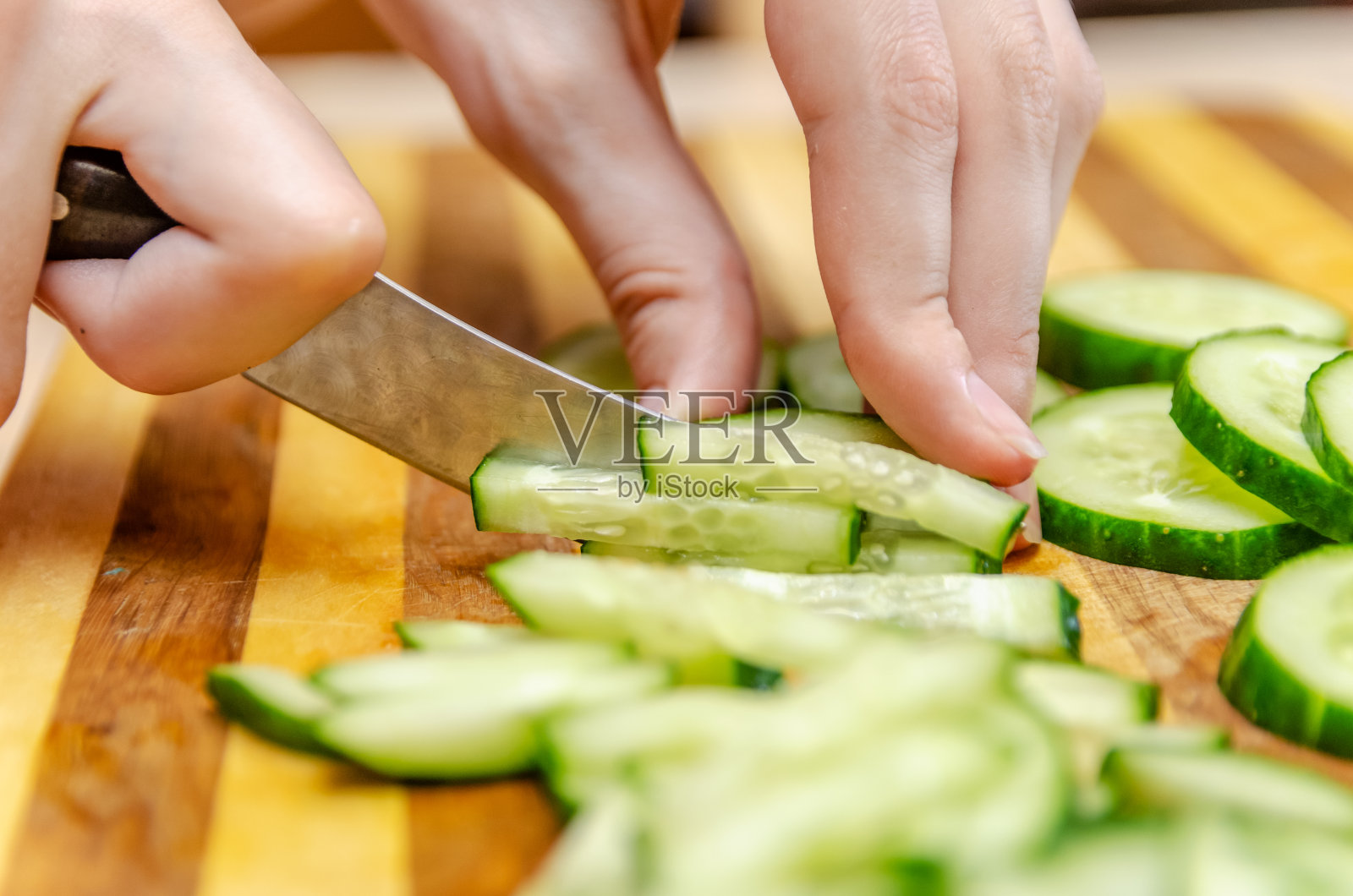 女用手在一块木板的栏杆上用刀切黄瓜照片摄影图片