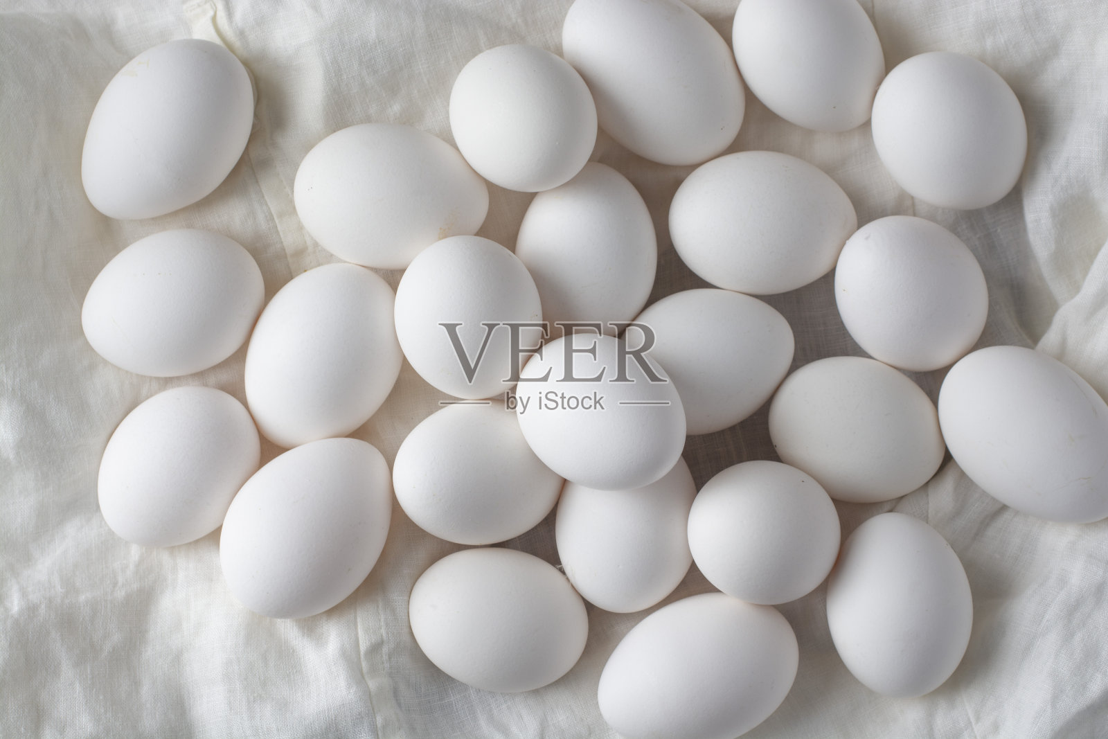 白色的鸡蛋放在白色的亚麻布上。从以上观点。照片摄影图片