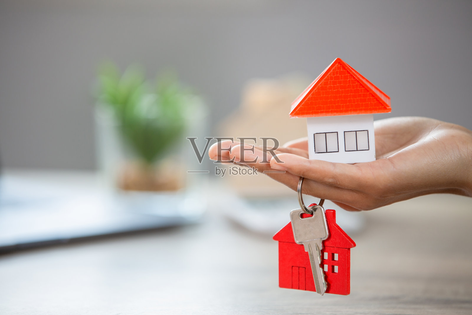 房地产经纪人手里拿着房子的钥匙，手上拿着房子。房地产的想法，搬家，或租赁房地产的家庭交易。照片摄影图片