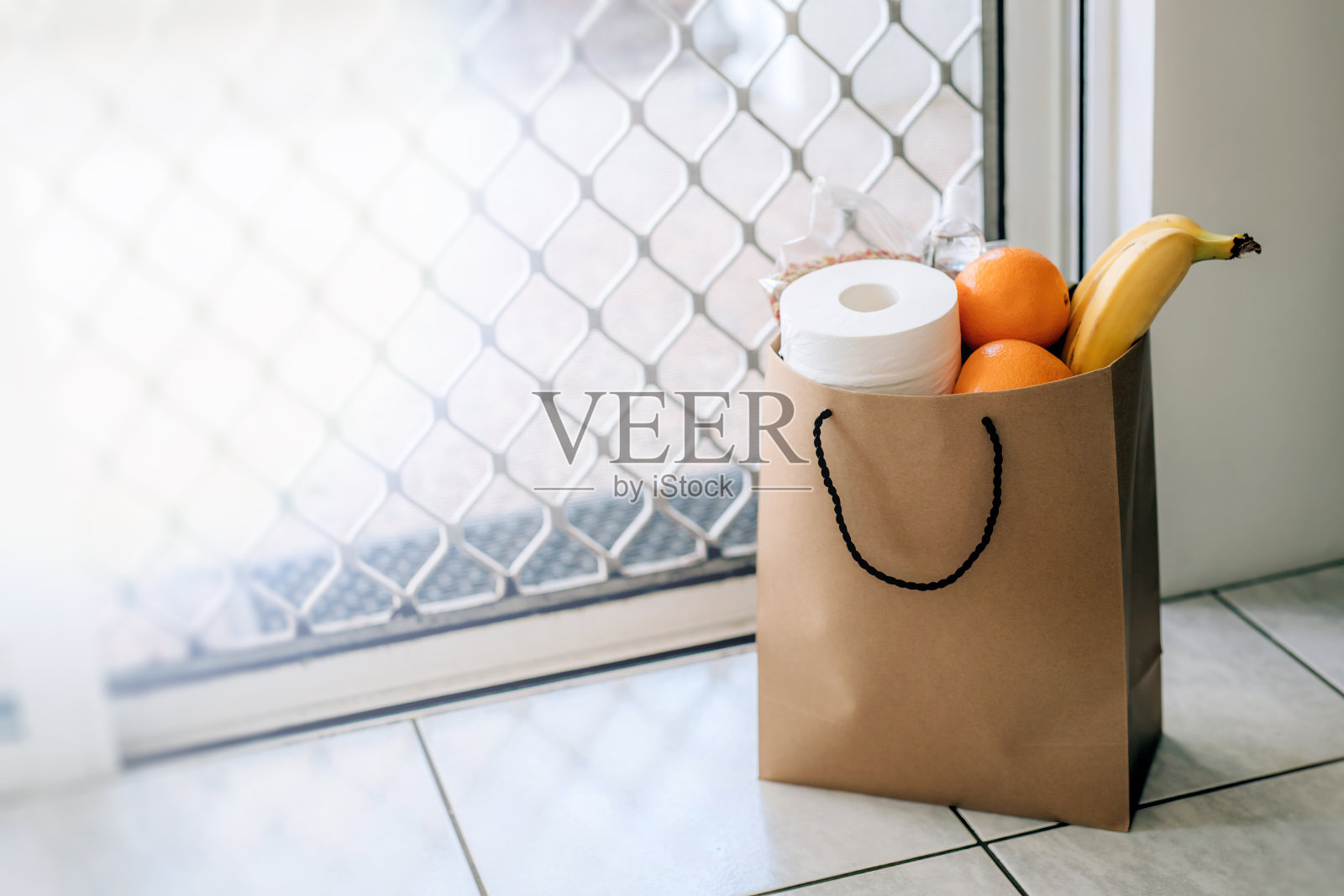 装着食物和厕纸的纸袋放在门口的地板上。照片摄影图片