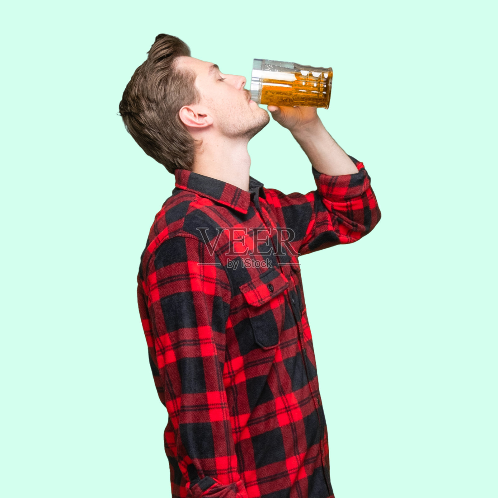 白人年轻男子站着，穿着伐木工衬衫，拿着马克杯照片摄影图片