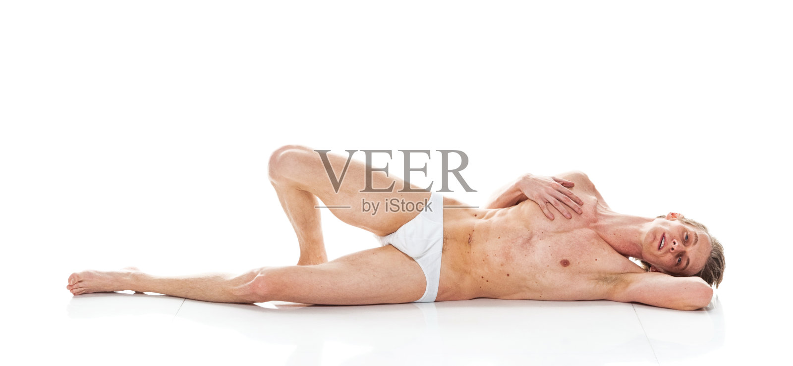 白人年轻男性穿着泳裤躺在白色背景前照片摄影图片