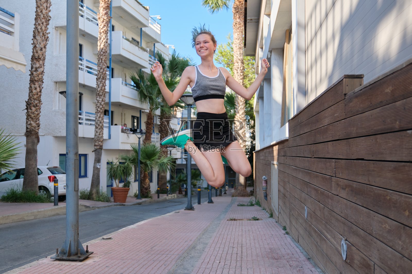 美丽的体育少女少女跳跃，在空中飞翔，街道背景照片摄影图片