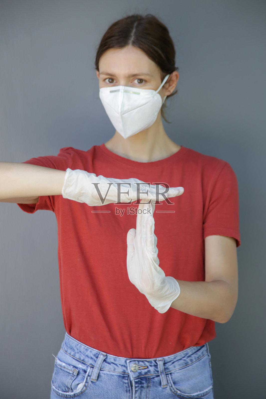 年轻白种妇女的肖像戴着防护医疗面具，并显示出时间出手势。暂停或中断时间手势。COVID - 19新型冠状病毒爆发或空气污染概念。照片摄影图片