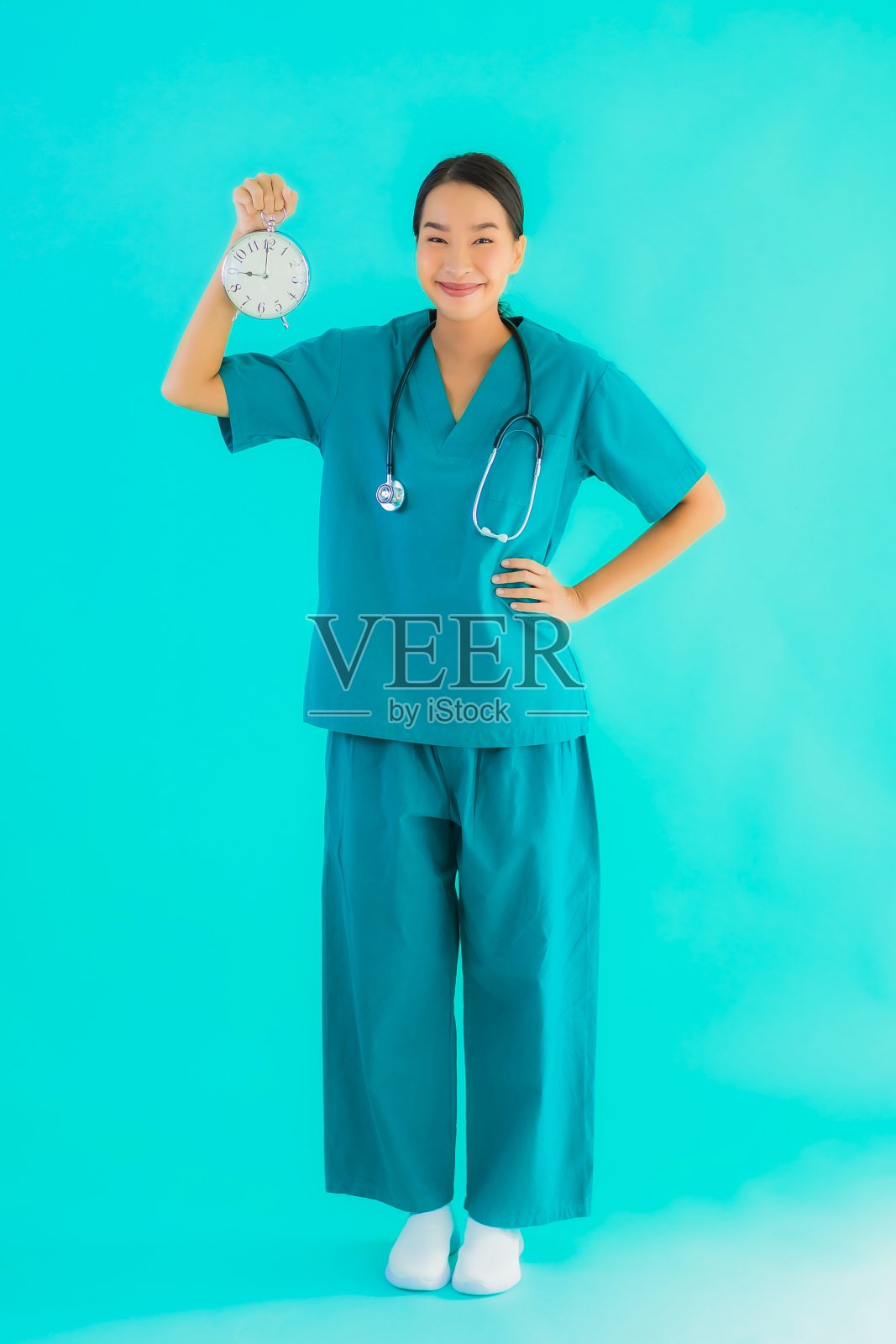 肖像美丽年轻的亚洲女医生显示时钟或闹钟照片摄影图片