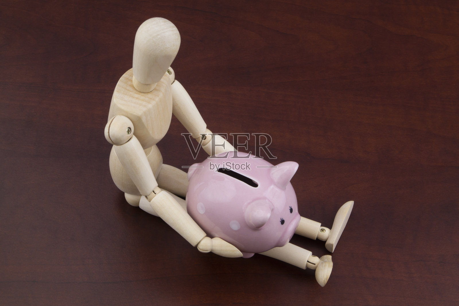 木头人手里拿着存钱罐照片摄影图片