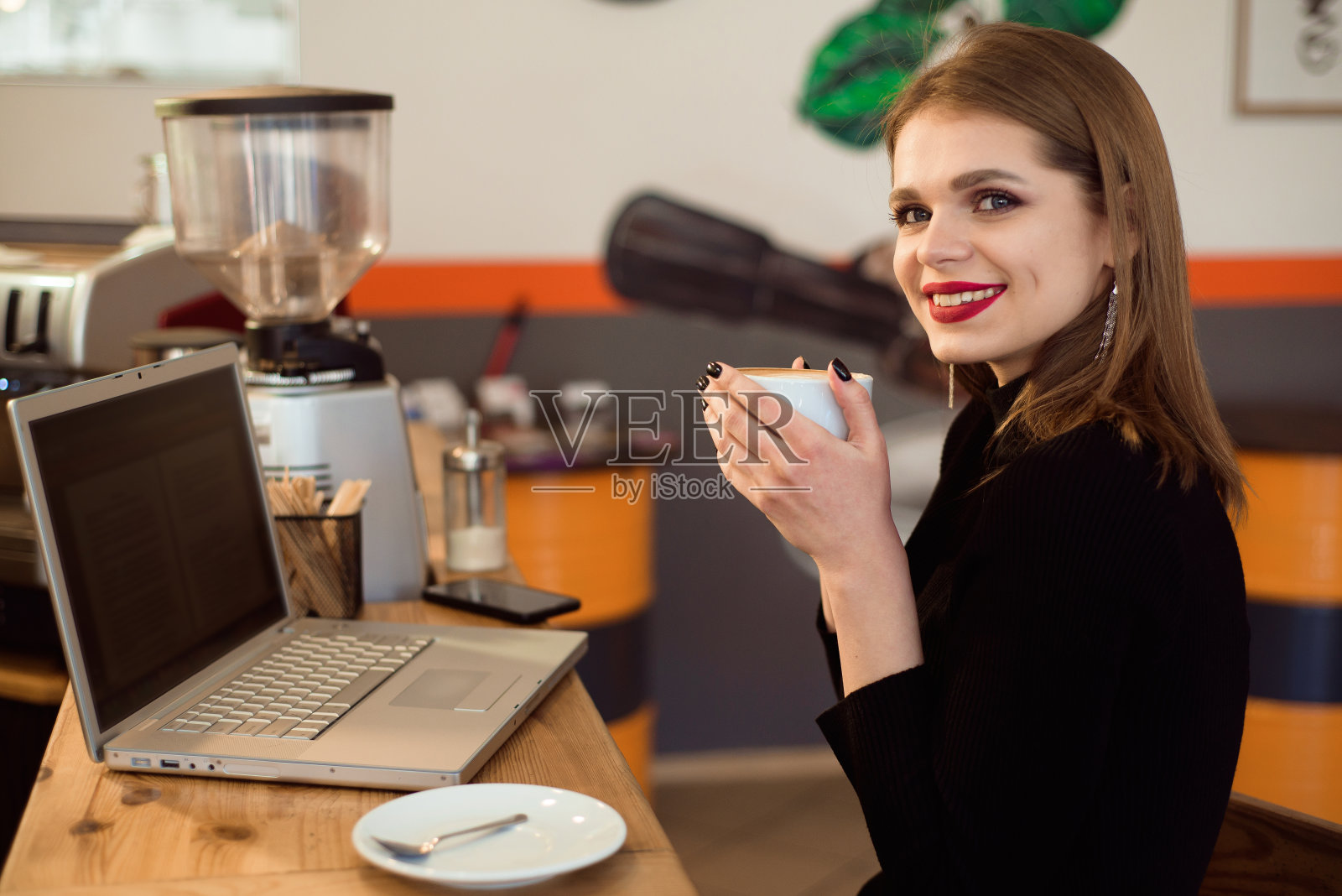 美丽的白种女人梦想着什么，而坐在便携式上网本在现代咖啡馆酒吧。照片摄影图片