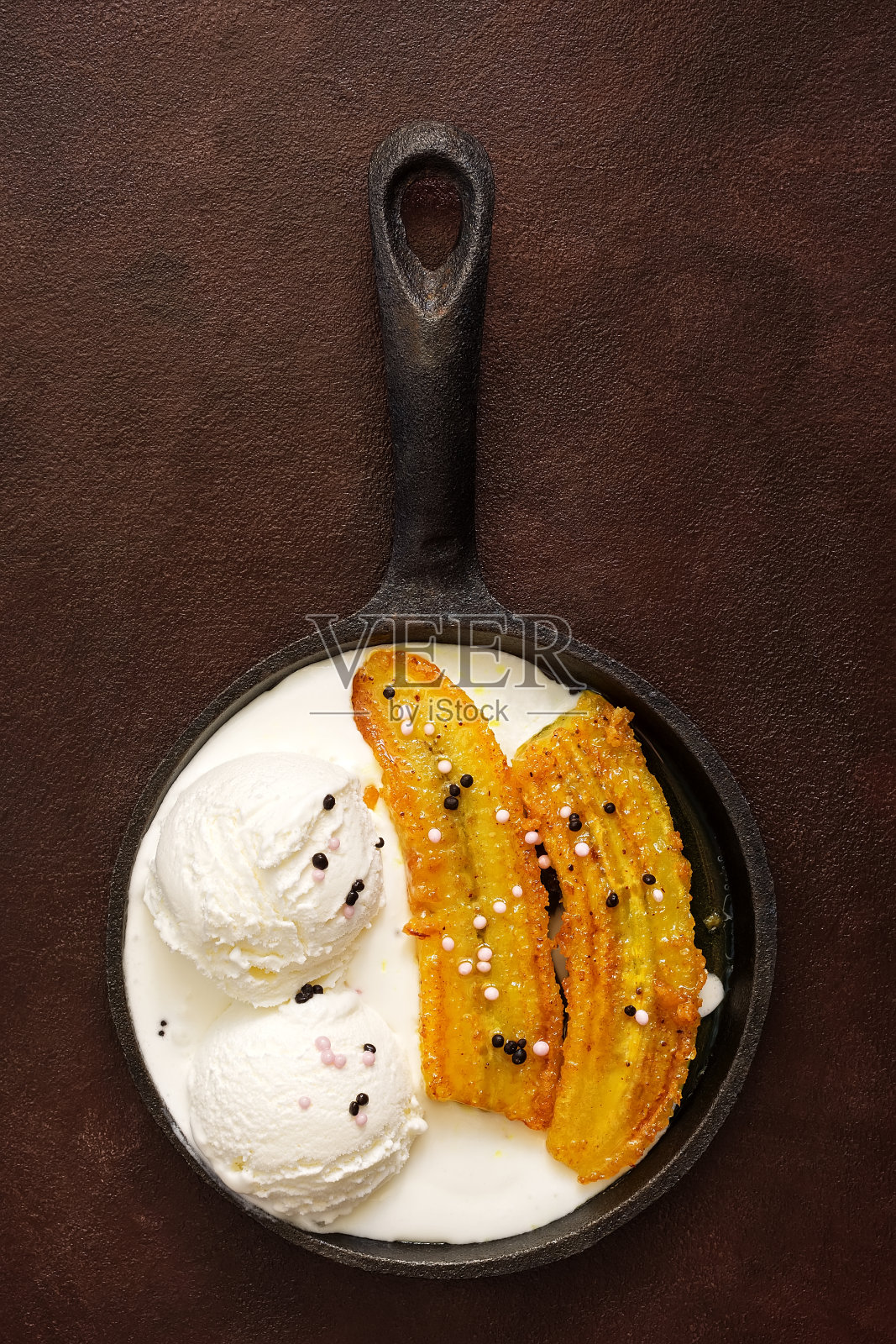 油炸香蕉和冰淇淋球在平底锅，在黑暗的乡村背景。美味可口的甜点。俯视图，平放照片摄影图片