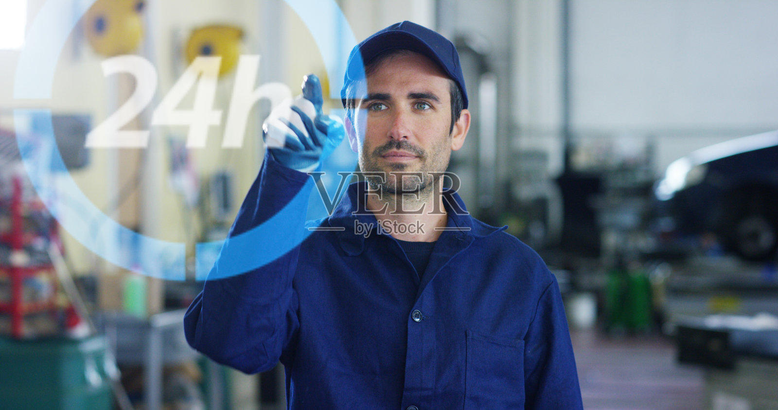 一个年轻英俊的汽车技师在一个汽车车间的肖像，而他正在使用未来的技术。照片摄影图片