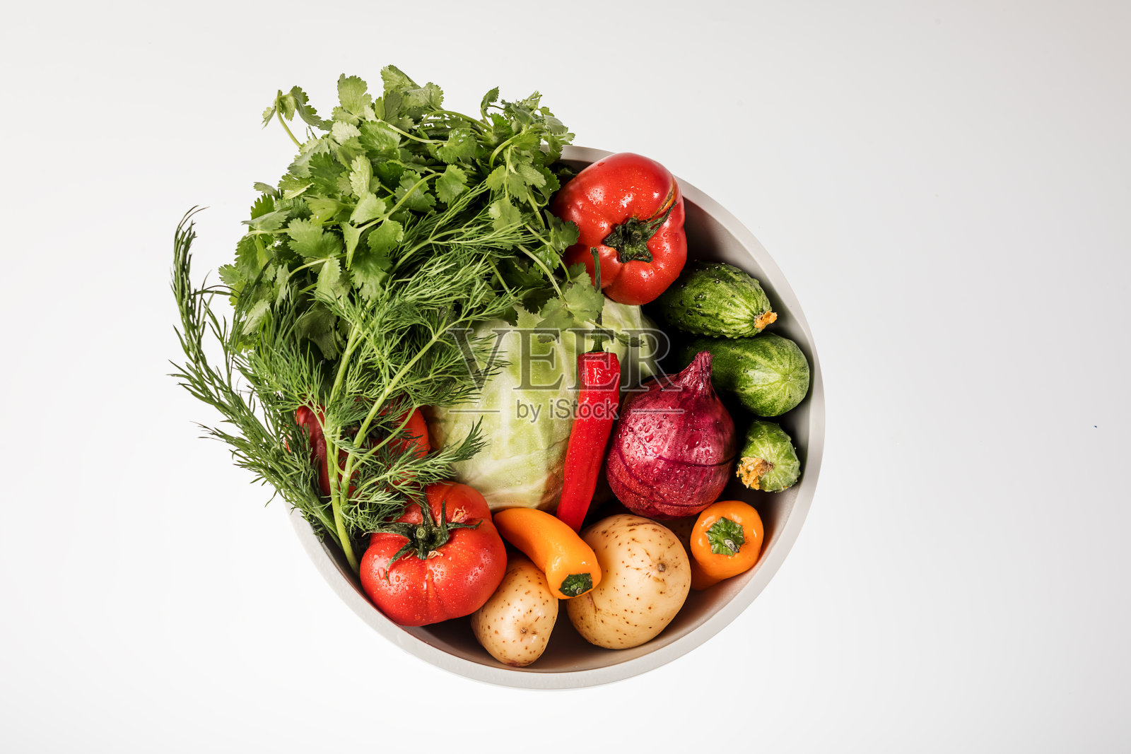 白色背景的圆碗里的蔬菜。照片摄影图片