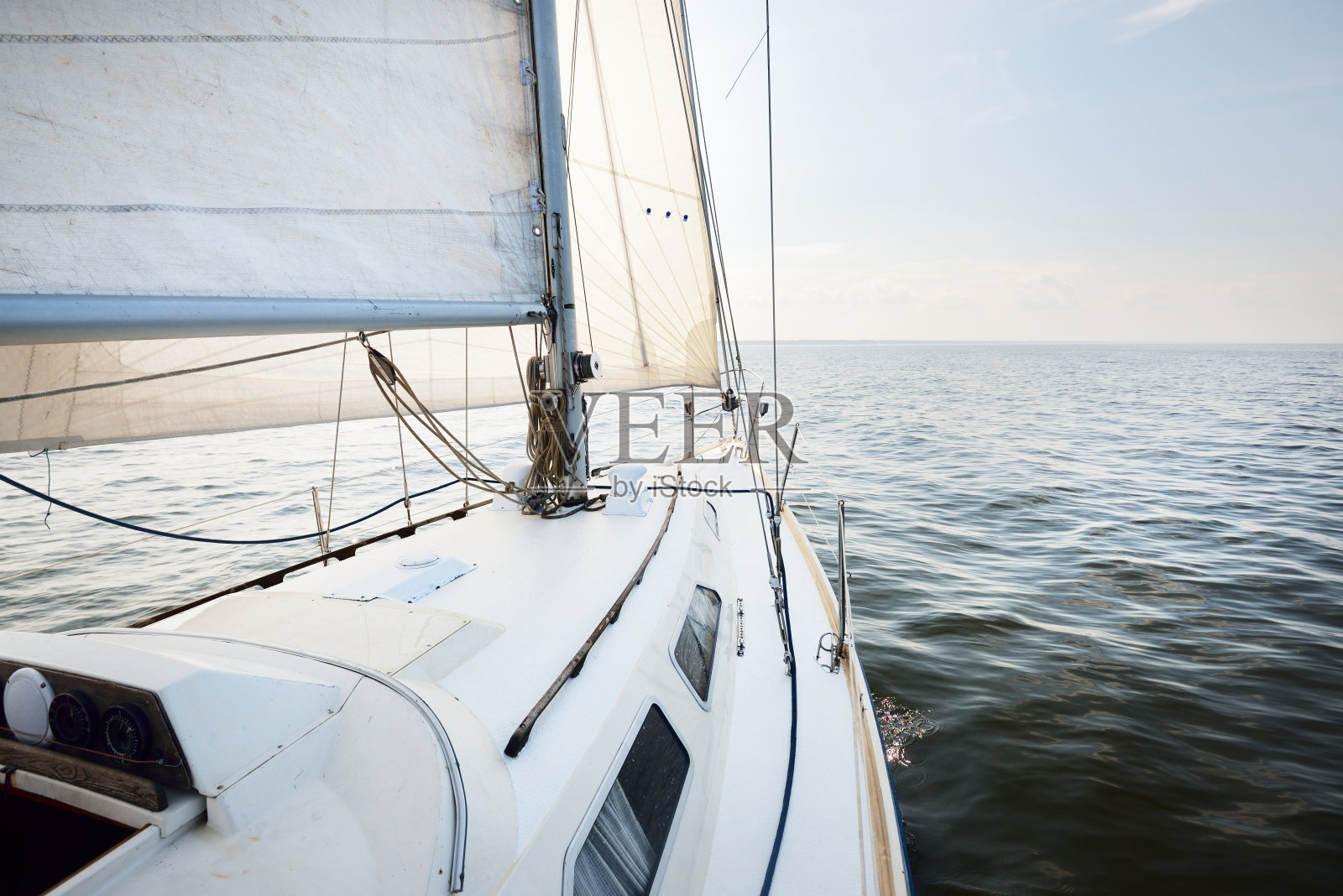 在一个晴朗的日子里，一艘白色游艇在公海上。从甲板上向下看，船头，桅杆和帆，索具设备的特写。夏季大西洋航行靠近西班牙和非洲照片摄影图片