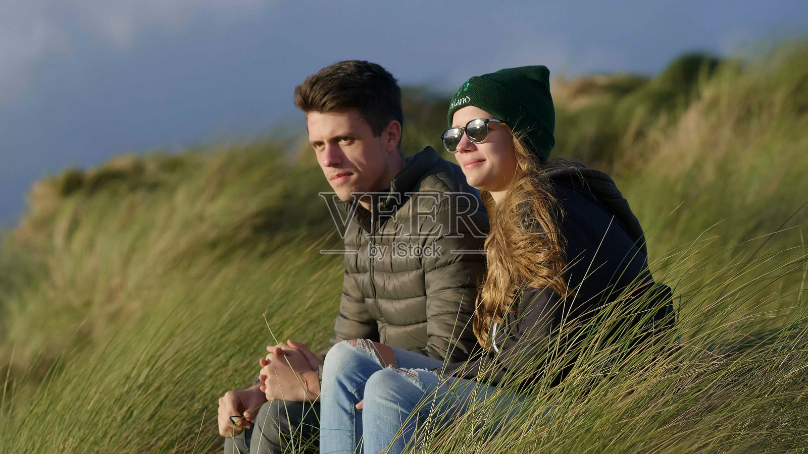 一对幸福的夫妇坐在水边的芦苇草丛里照片摄影图片