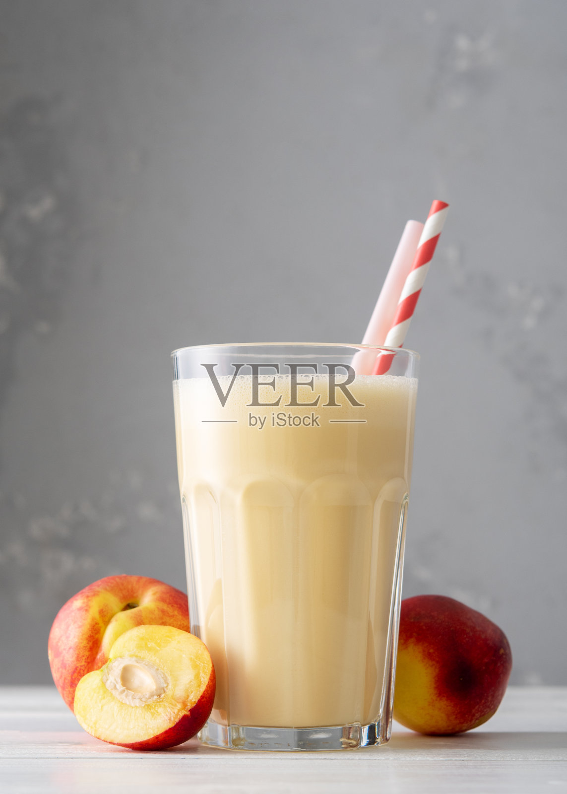 在白色木桌上，用油桃或桃子混合新鲜蛋白质。新鲜杏奶昔。一杯桃子奶昔。照片摄影图片