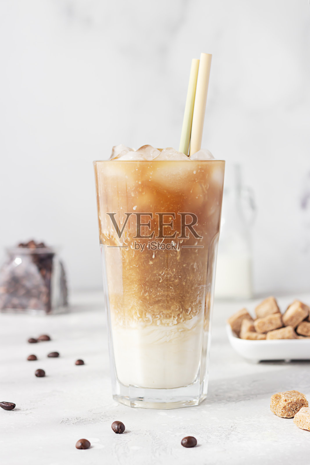 冰咖啡在一个高脚杯与奶油被倒入显示其质地的饮料。冰咖啡加冰块。照片摄影图片