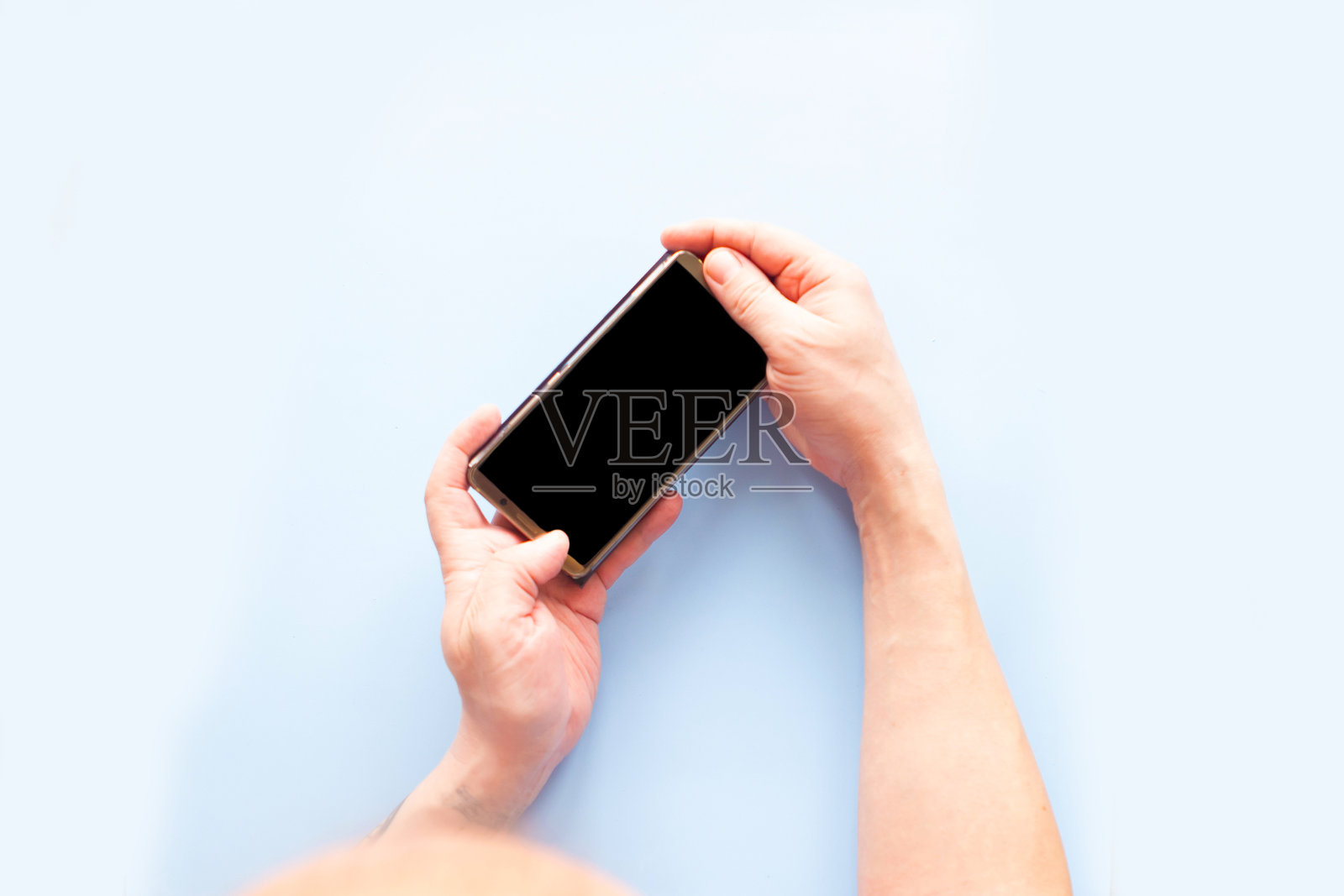 男子拿着黑屏模拟手机，蓝色背景，俯视图照片摄影图片