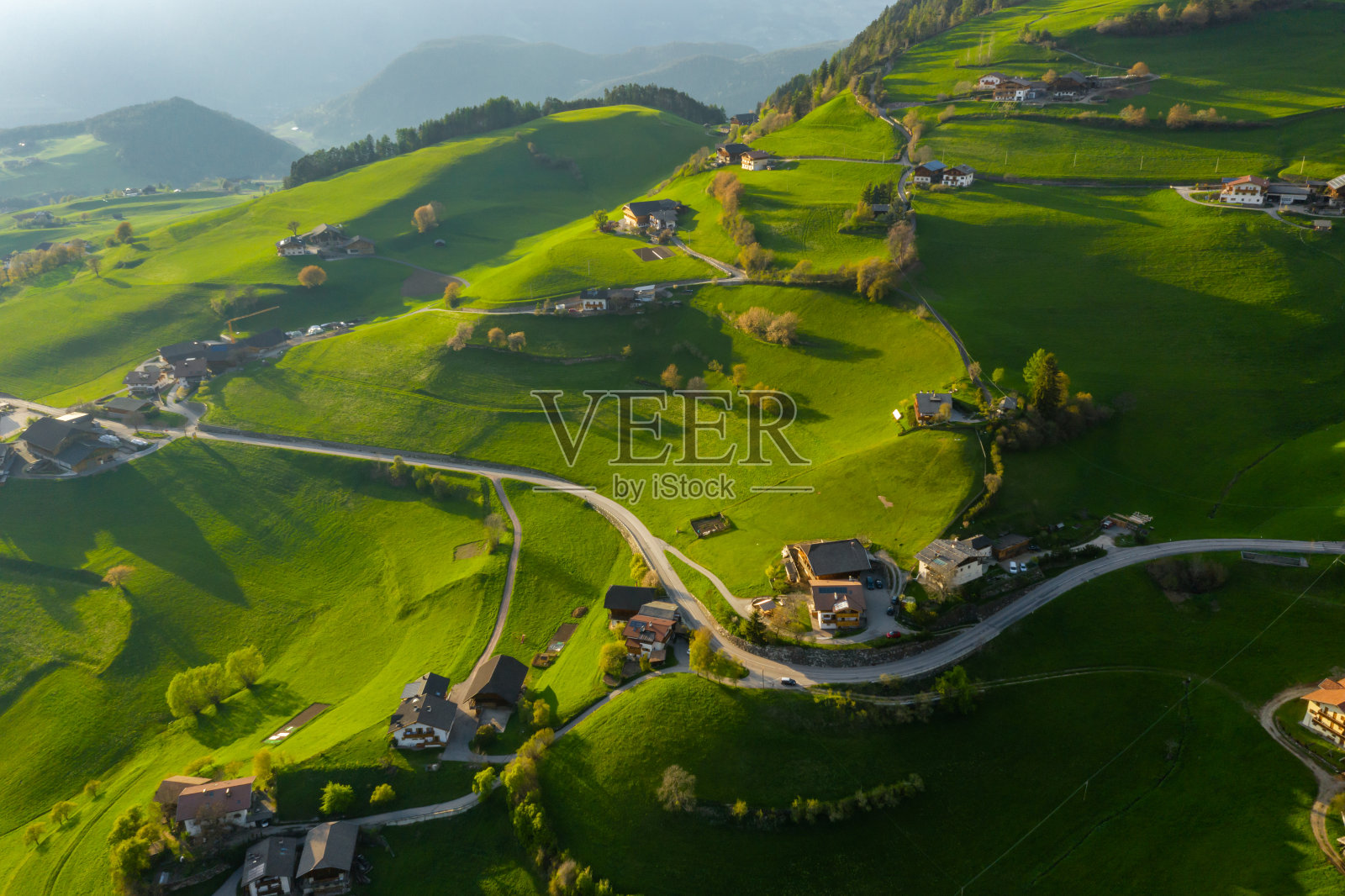 鸟瞰图不可思议的绿色草地的意大利阿尔卑斯山，绿色的山坡，博尔扎诺，巨大的云在一个山谷，屋顶的屋顶，白云石的背景，阳光透过云照片摄影图片