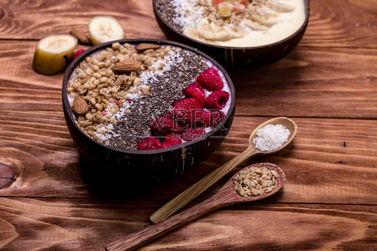 冰沙碗里放着树莓和奇亚籽，上面放着冰冻的浆果和格兰诺拉麦片。天然椰子中的健康营养照片摄影图片