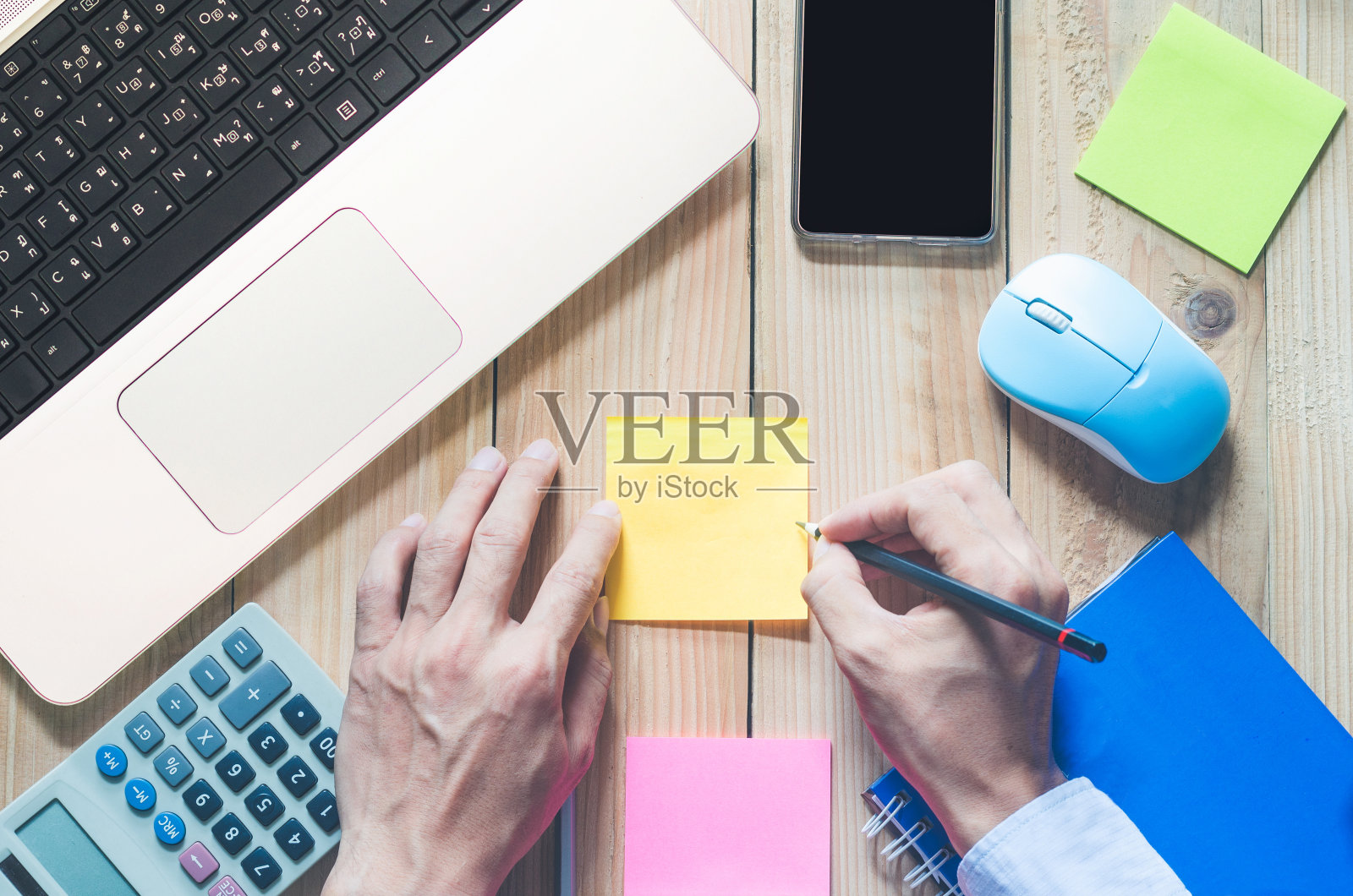 俯视图办公桌。商务人士在工作空间使用铅笔写便利贴与复印空间在木头桌子上。照片摄影图片