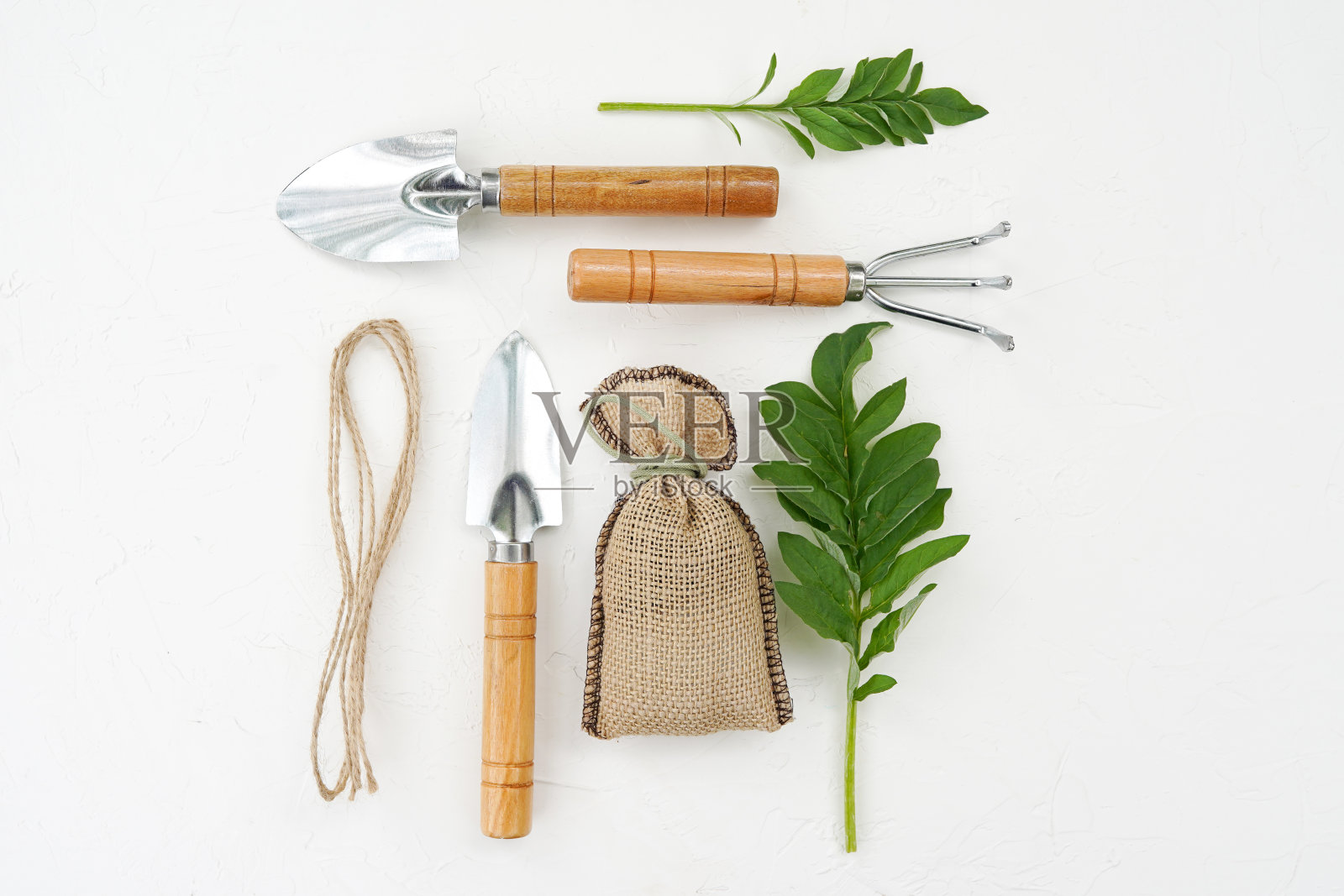 白色的旧桌子上放着绿叶的园艺工具。照片摄影图片