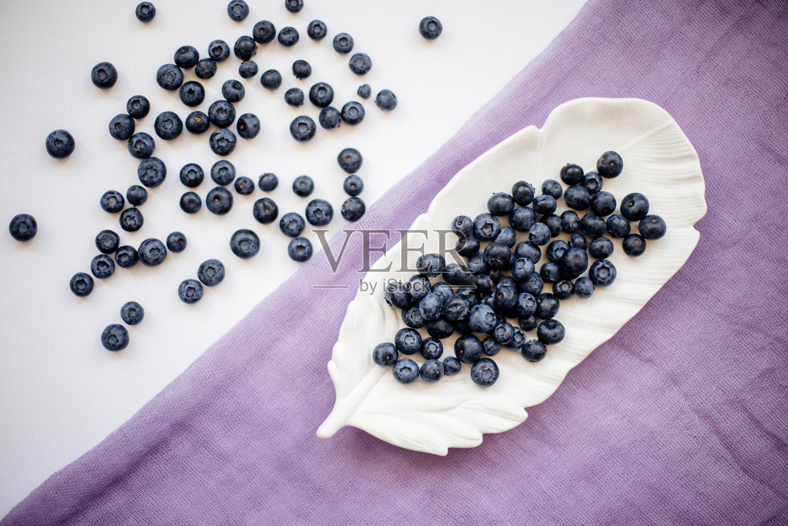 白色的桌子上放着蓝莓。照片摄影图片