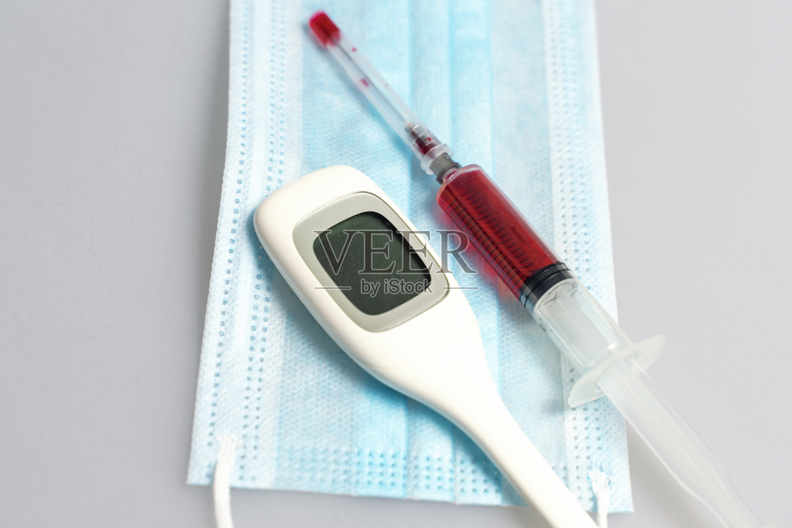 注射器用红色液体，一次性口罩，药片在一个水泡，空水泡为药片，电子温度计照片摄影图片