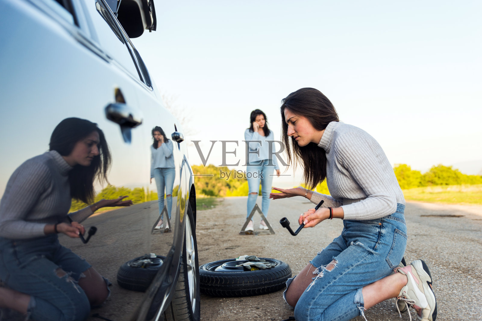 两个年轻女孩在路上遇到汽车故障，正在用手机呼叫紧急服务照片摄影图片