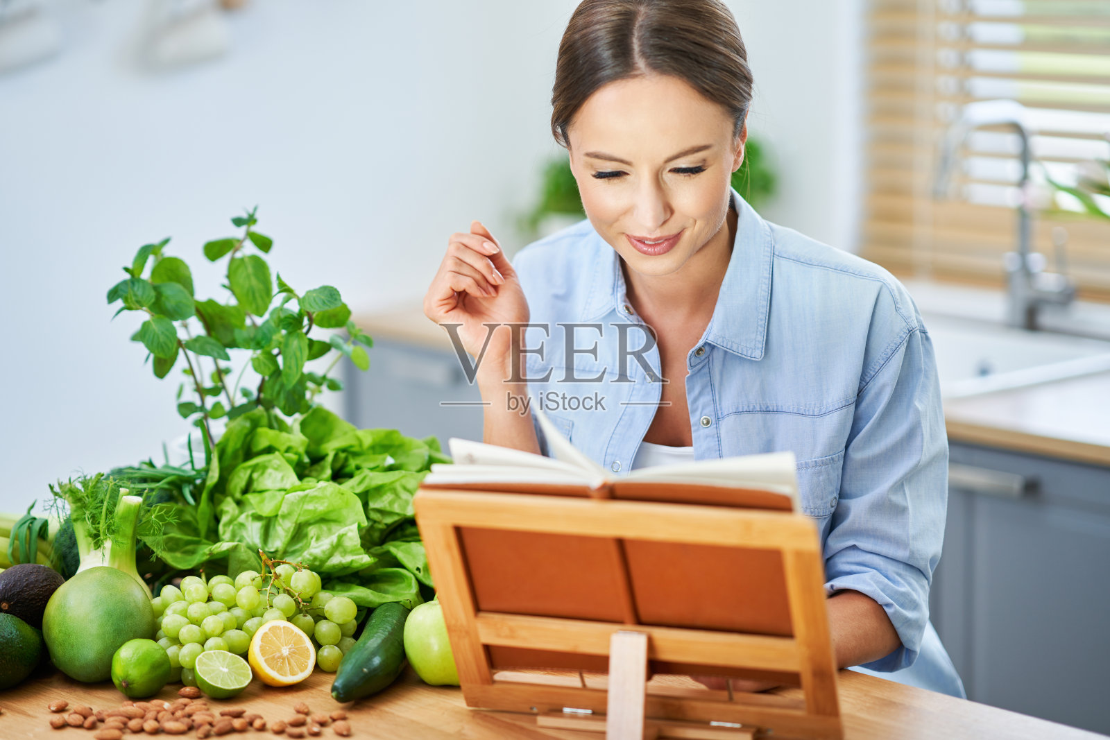 健康的成年女性，厨房里有绿色食物照片摄影图片