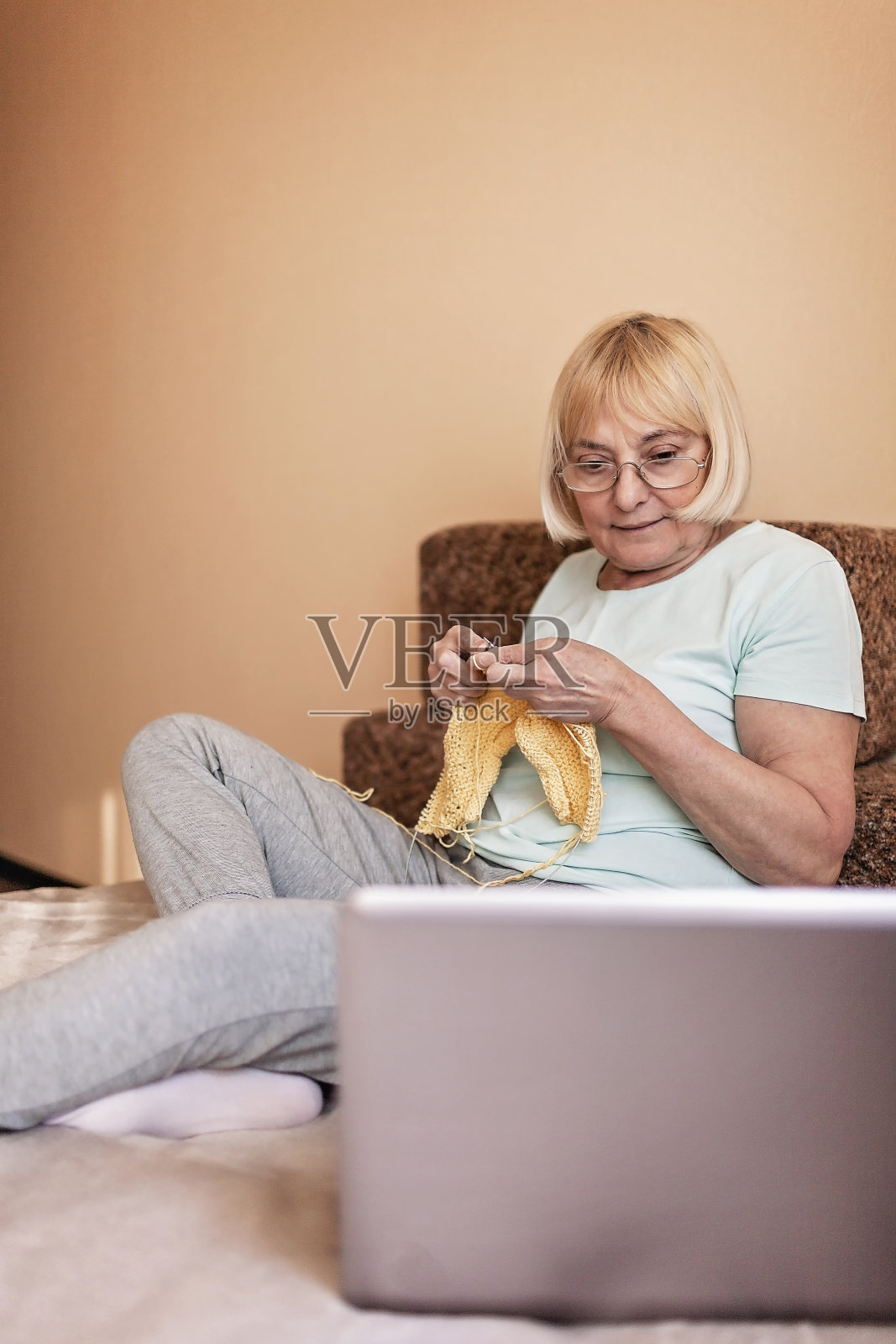 妇女坐在沙发上织毛衣在家隔离期间，上网爱好照片摄影图片