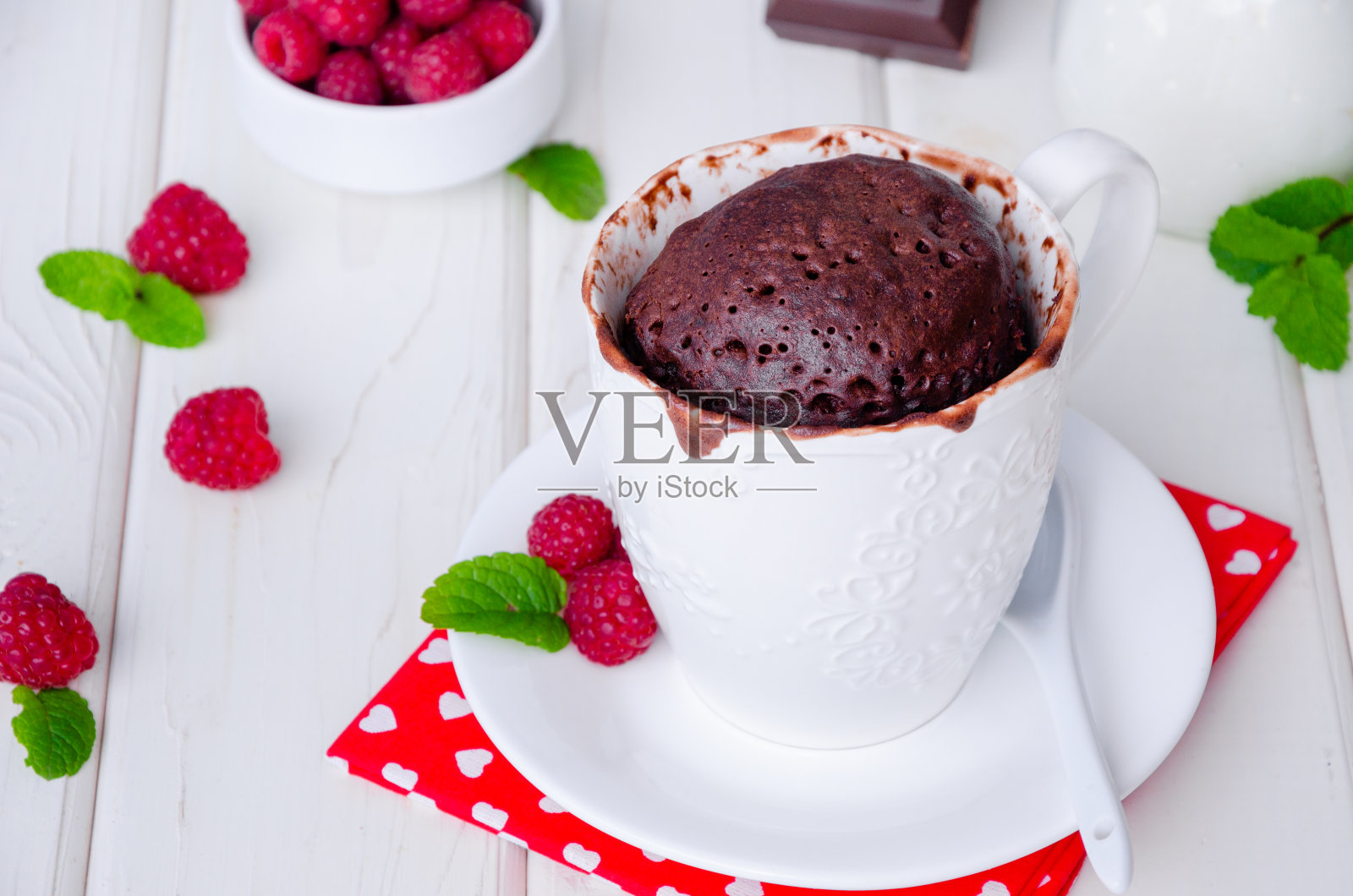 白色木质背景上的巧克力杯子蛋糕，上面有掼奶油、巧克力片和新鲜的覆盆子。照片摄影图片