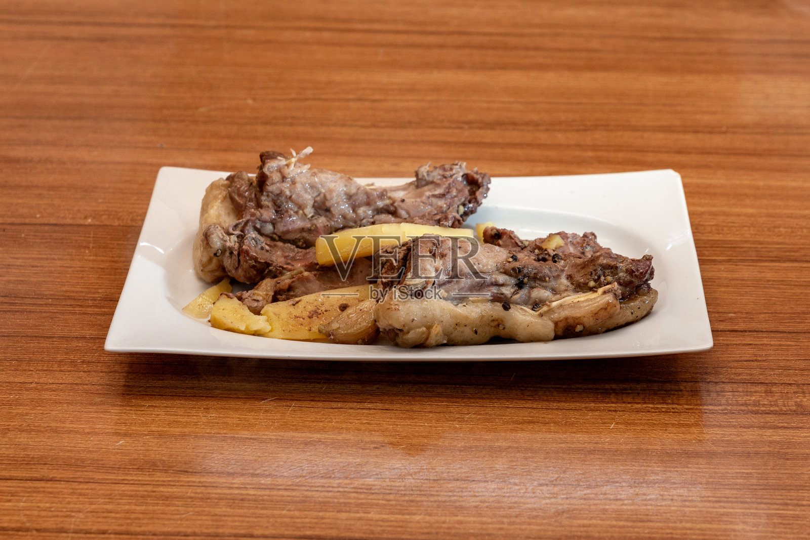木桌上的白色盘子里;烤内脏和土豆-烤马铃薯照片摄影图片