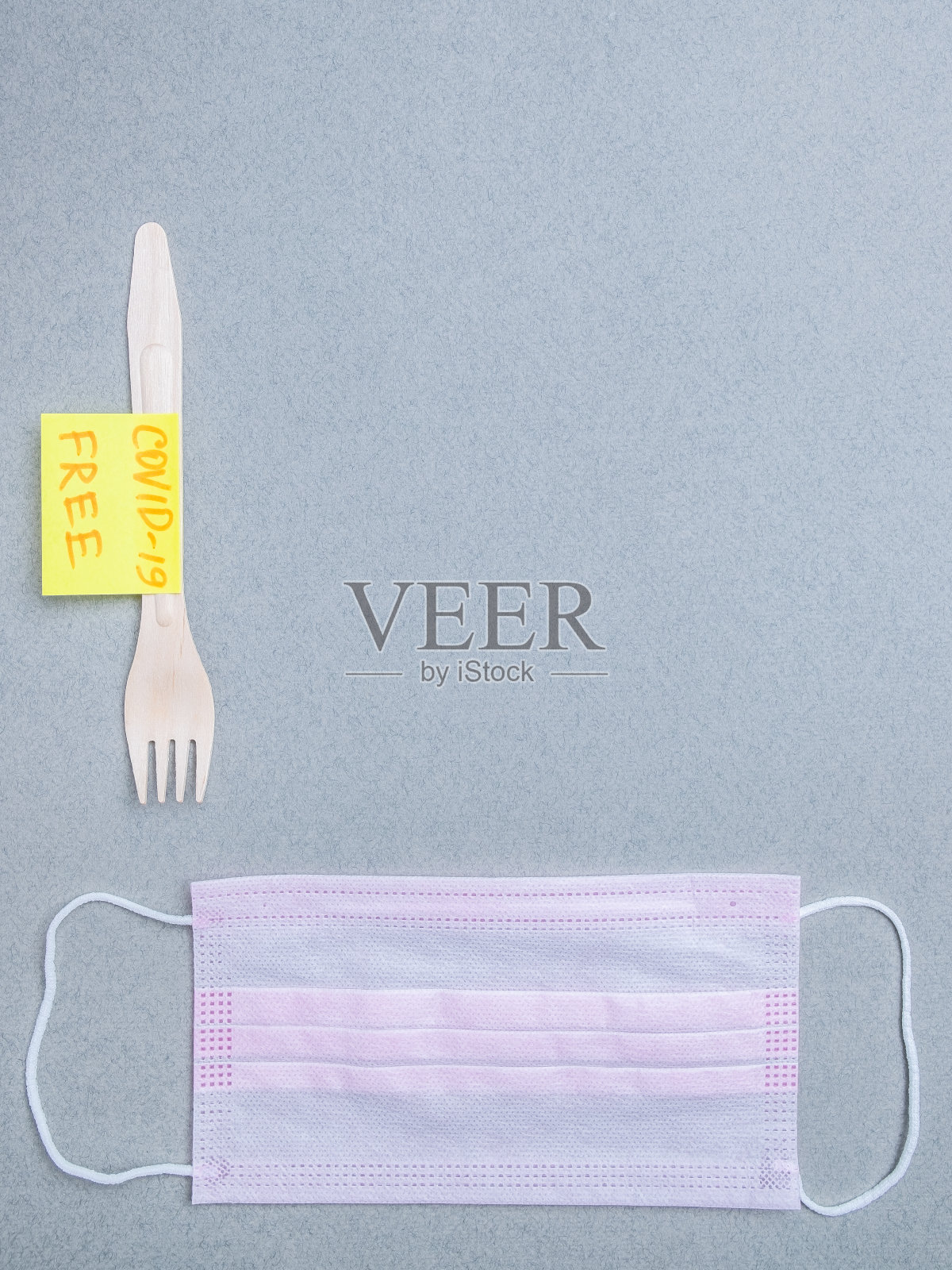 木质叉子、蓝色医用口罩和标有“covid-19免费”字样的贴纸。平的。照片摄影图片