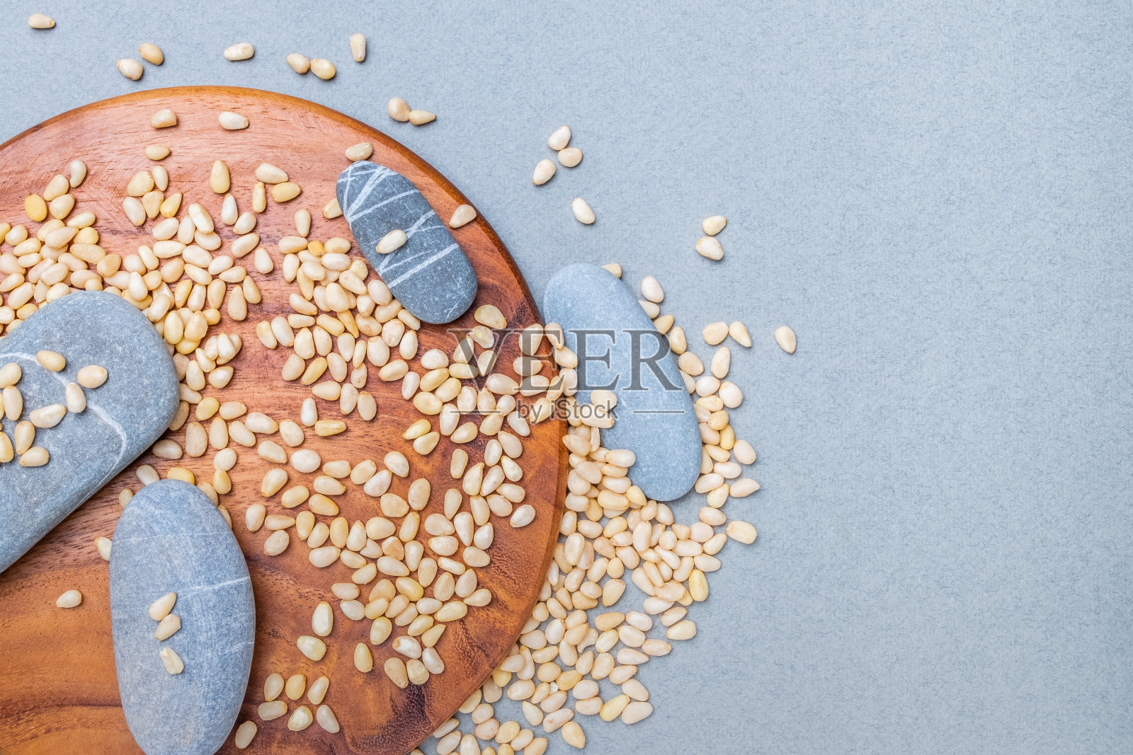 平的。椭圆形的灰色石头放在一个木制的架子上，背景是灰色的西伯利亚雪松坚果。照片摄影图片