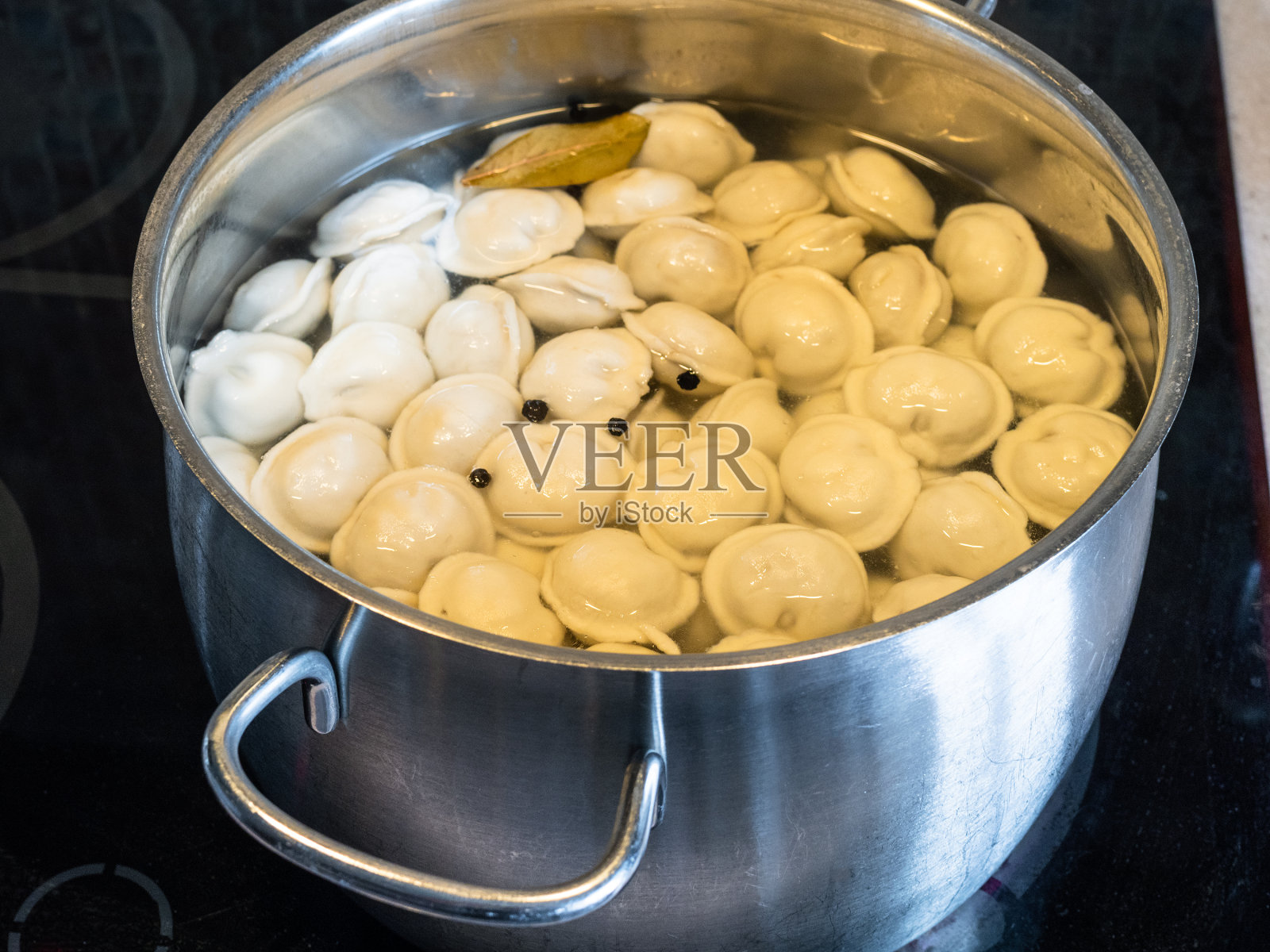 在陶瓷炉上的钢炖锅里烹饪帕尔梅尼照片摄影图片