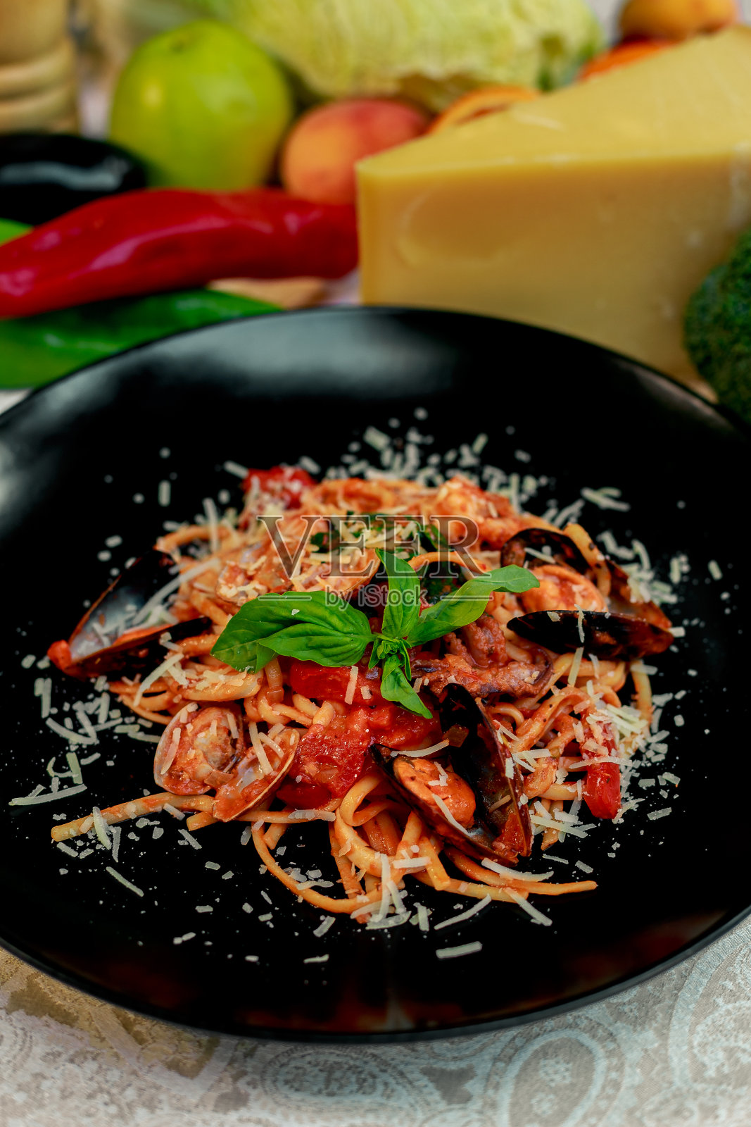 用帕尔玛干酪和海鲜搭配的意大利面食，黑色的盘子里有章鱼、虾和贻贝照片摄影图片