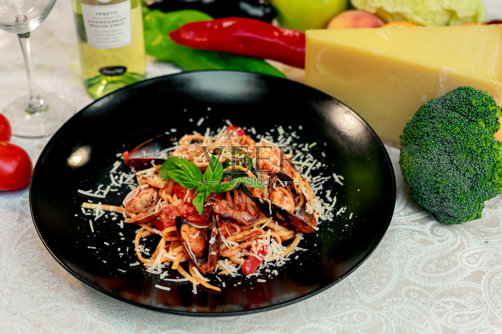 用帕尔玛干酪和海鲜搭配的意大利面食，黑色的盘子里有章鱼、虾和贻贝照片摄影图片