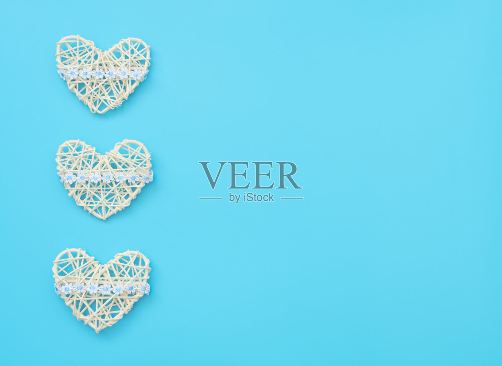 白色藤心与丝带与花在蓝色的背景。母亲节，情人节，婚礼，生日或其他合适的事件庆祝贺卡的概念。平铺与复制空间的文本。照片摄影图片