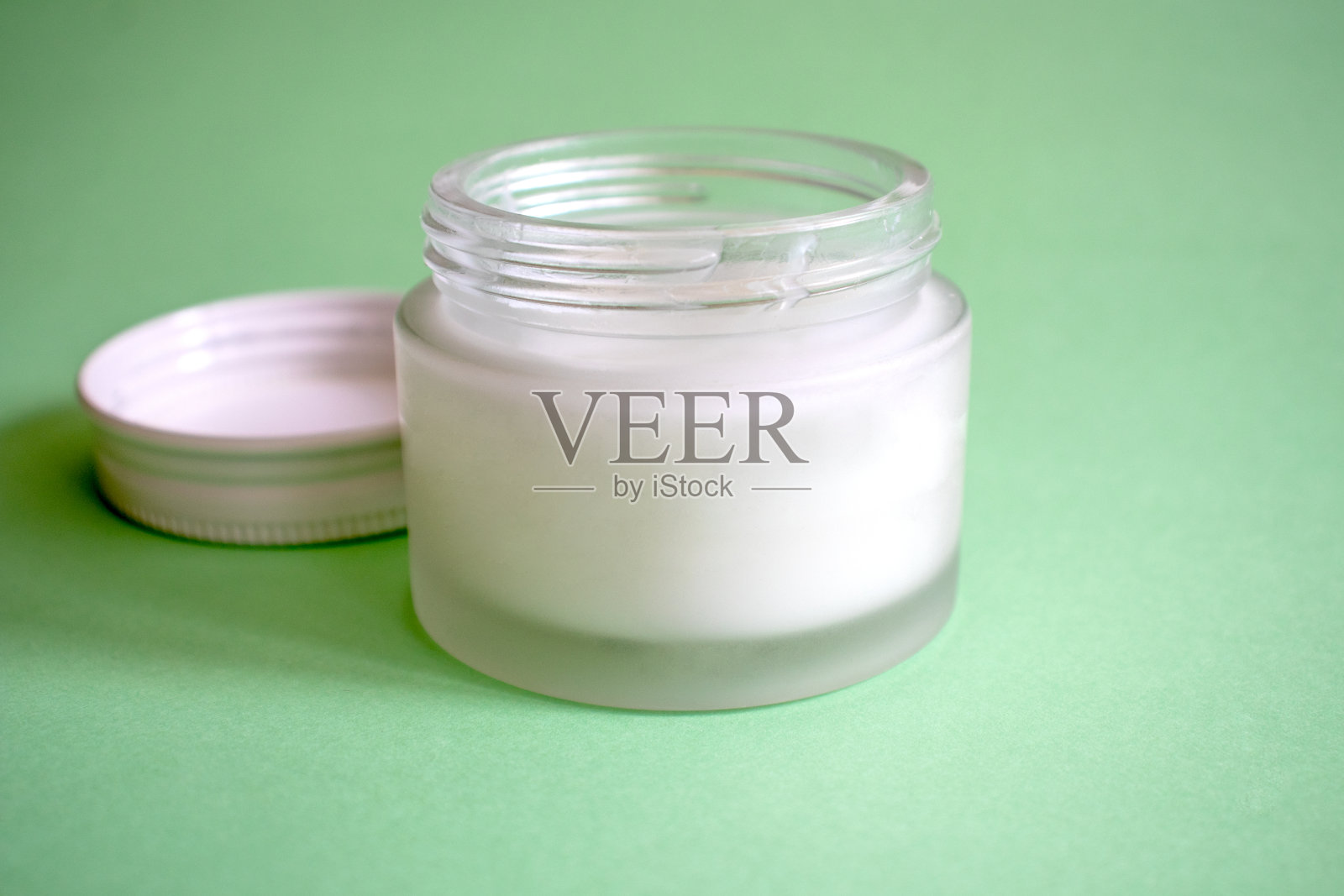 在绿色背景上隔离的化妆品玻璃容器。免费的塑料。美丽的概念。照片摄影图片